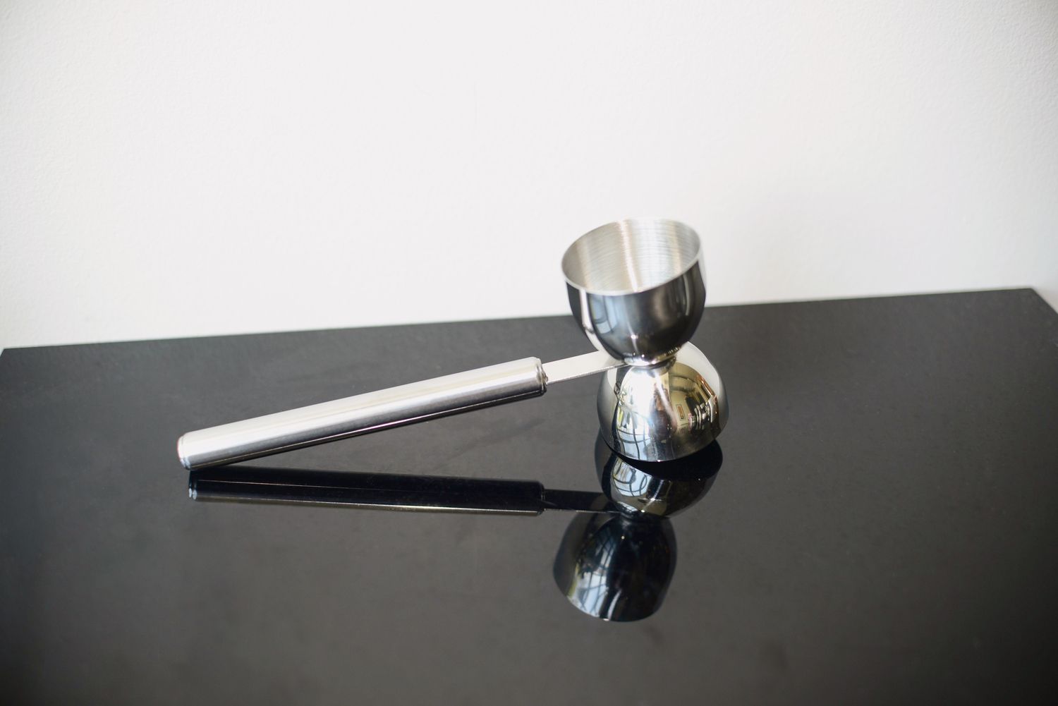 a double-sided, handled jigger on a black countertop
