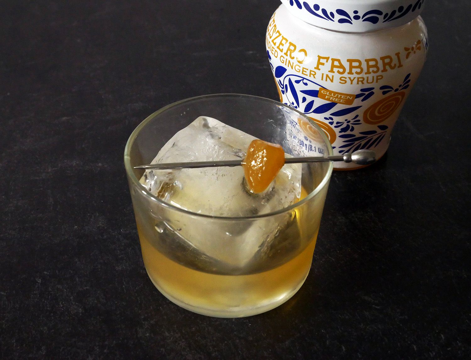 Old fashioned cocktail with stem ginger on a metal cocktail skewer.