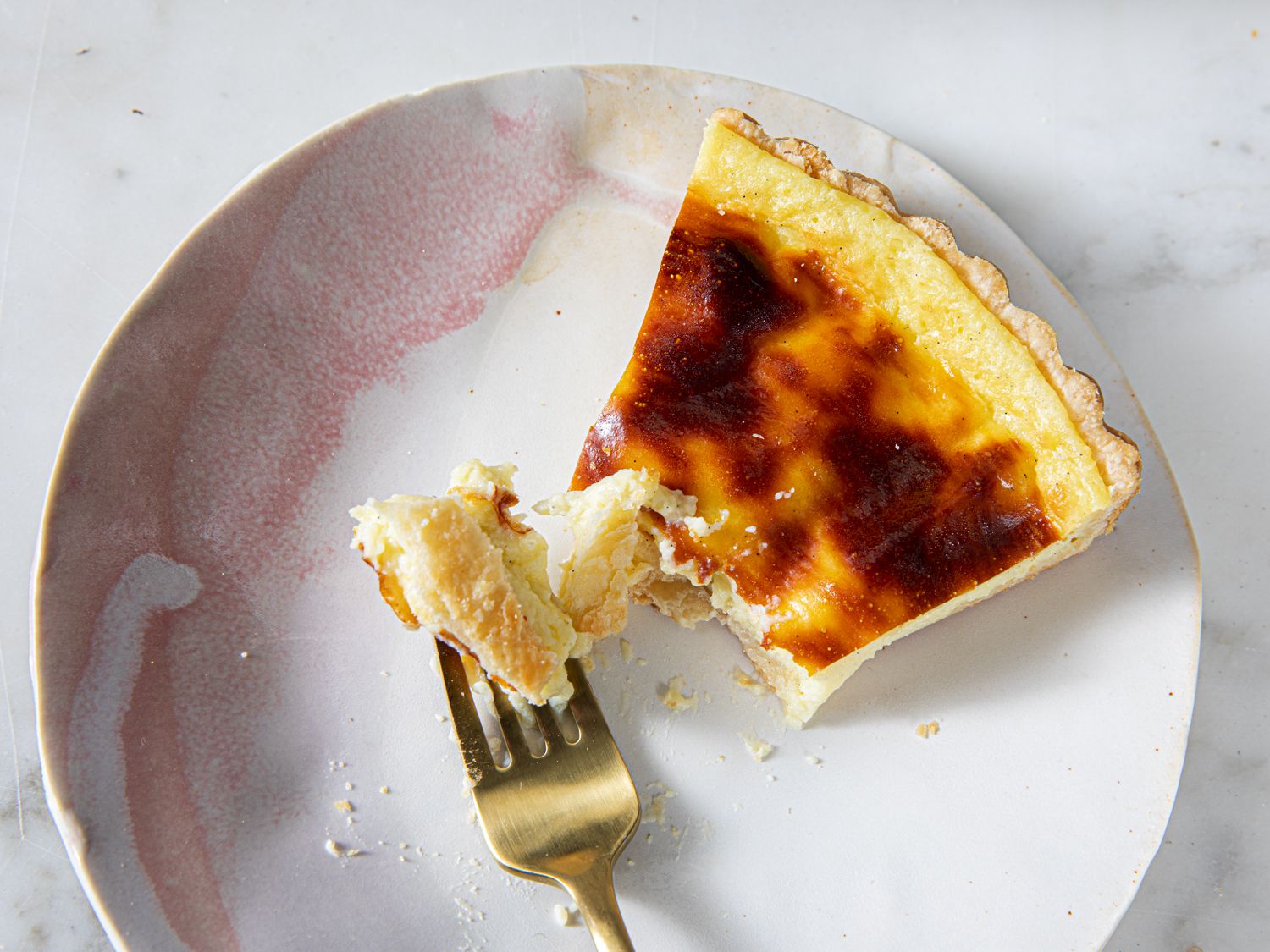 A fork on a plate next to a half eaten Flan Pâtissier