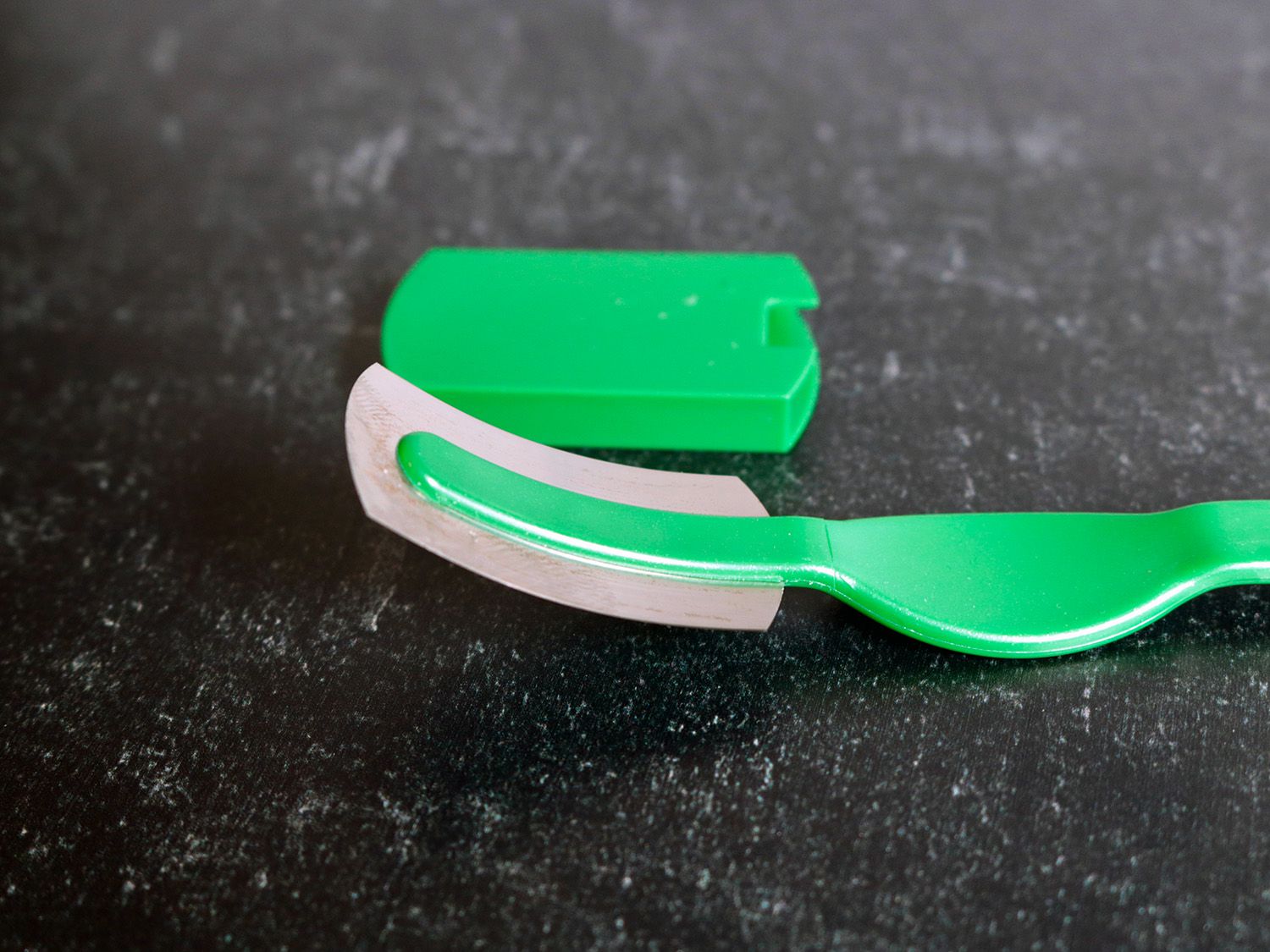 The head of a plastic bread lame with a fixed angle blade.