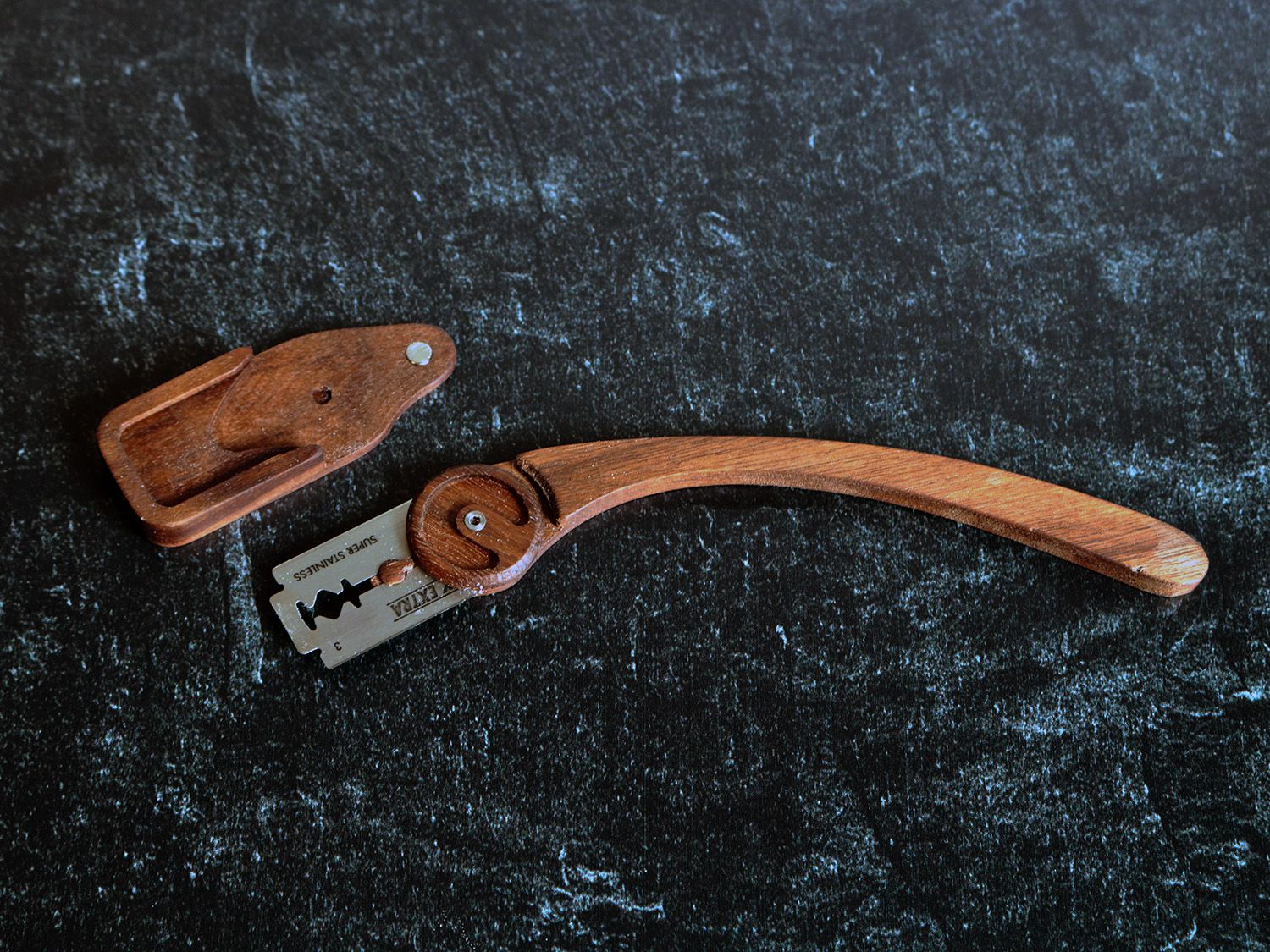 A thin, curved, wooden handle with an attached razor blade designed to score bread dough.