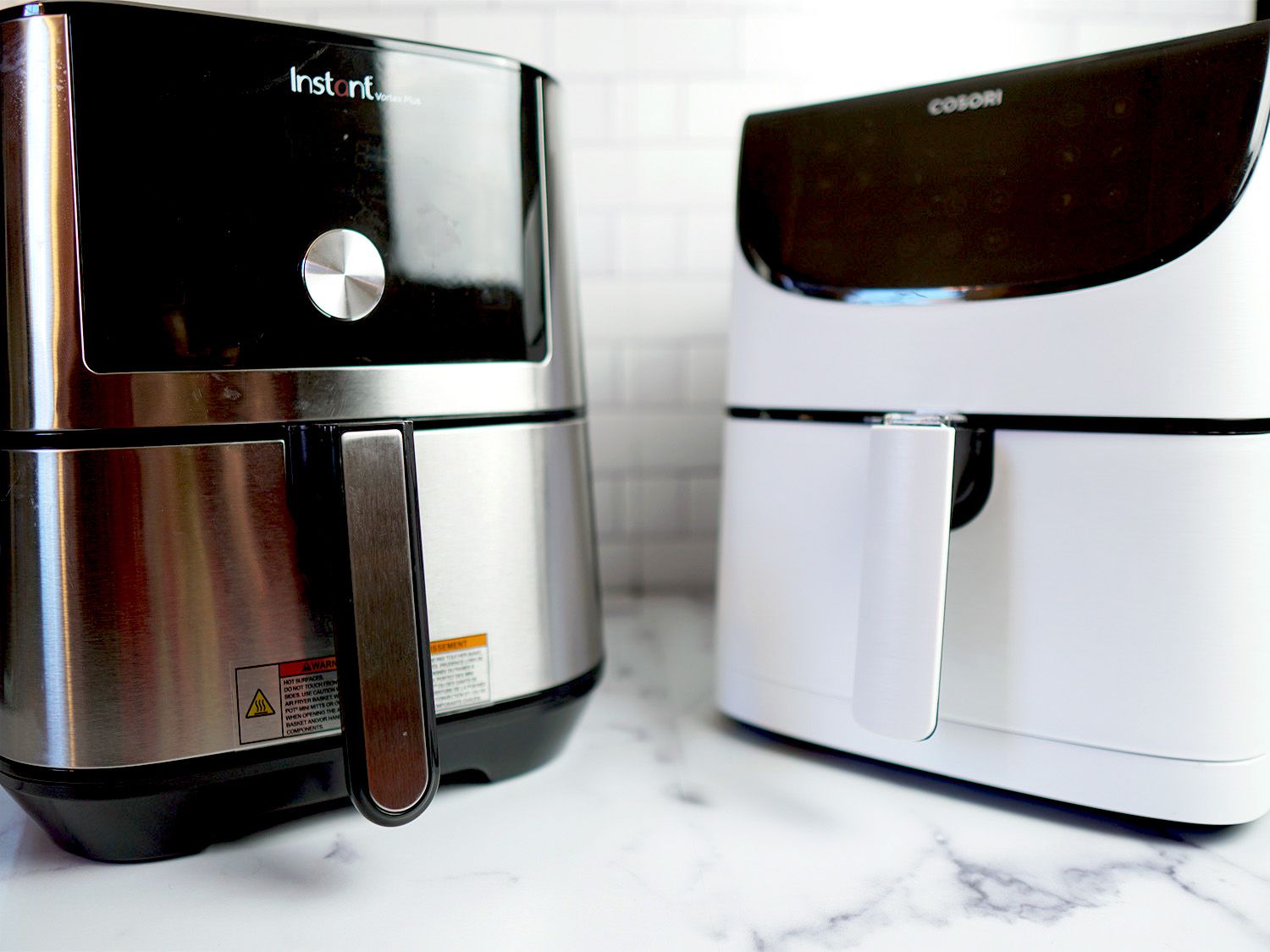 two air fryers side-by-side on a marble surface