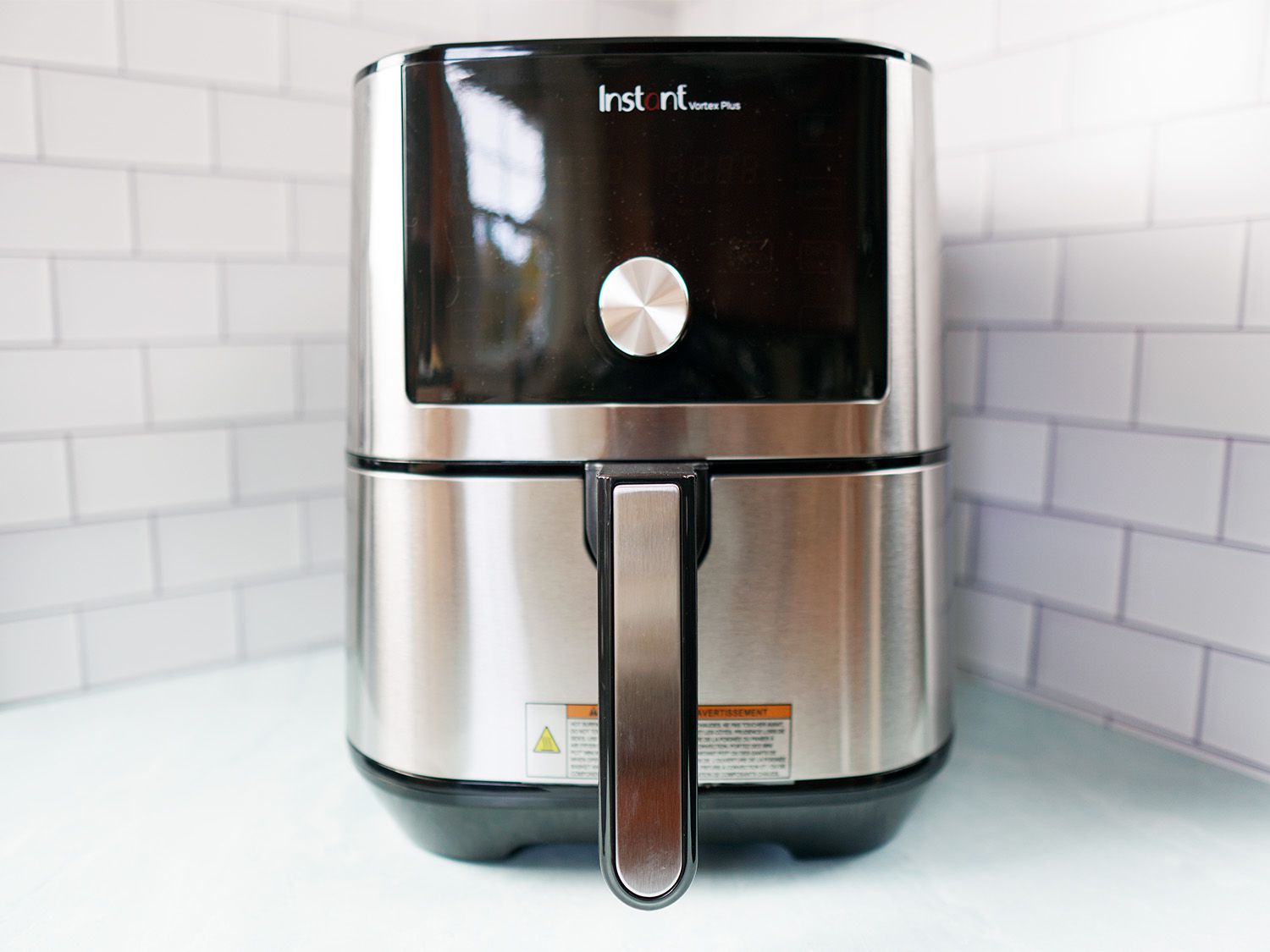 a silver and black air fryer on a blue surface