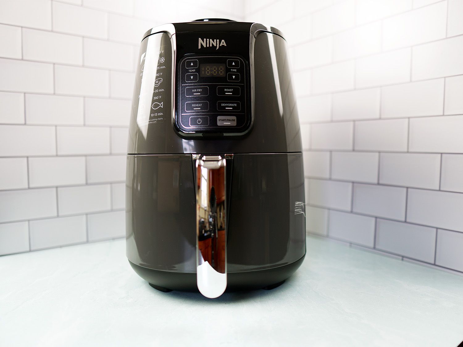 A grey and silver air fryer sitting on a blue surface