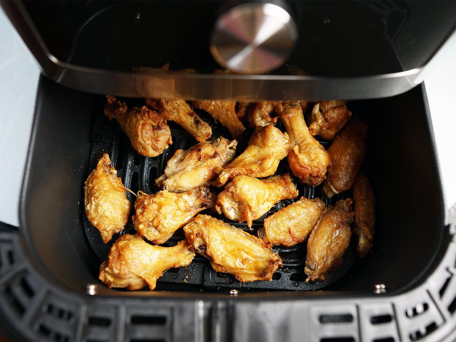chicken wings in an air fryer basket that's partially pulled out