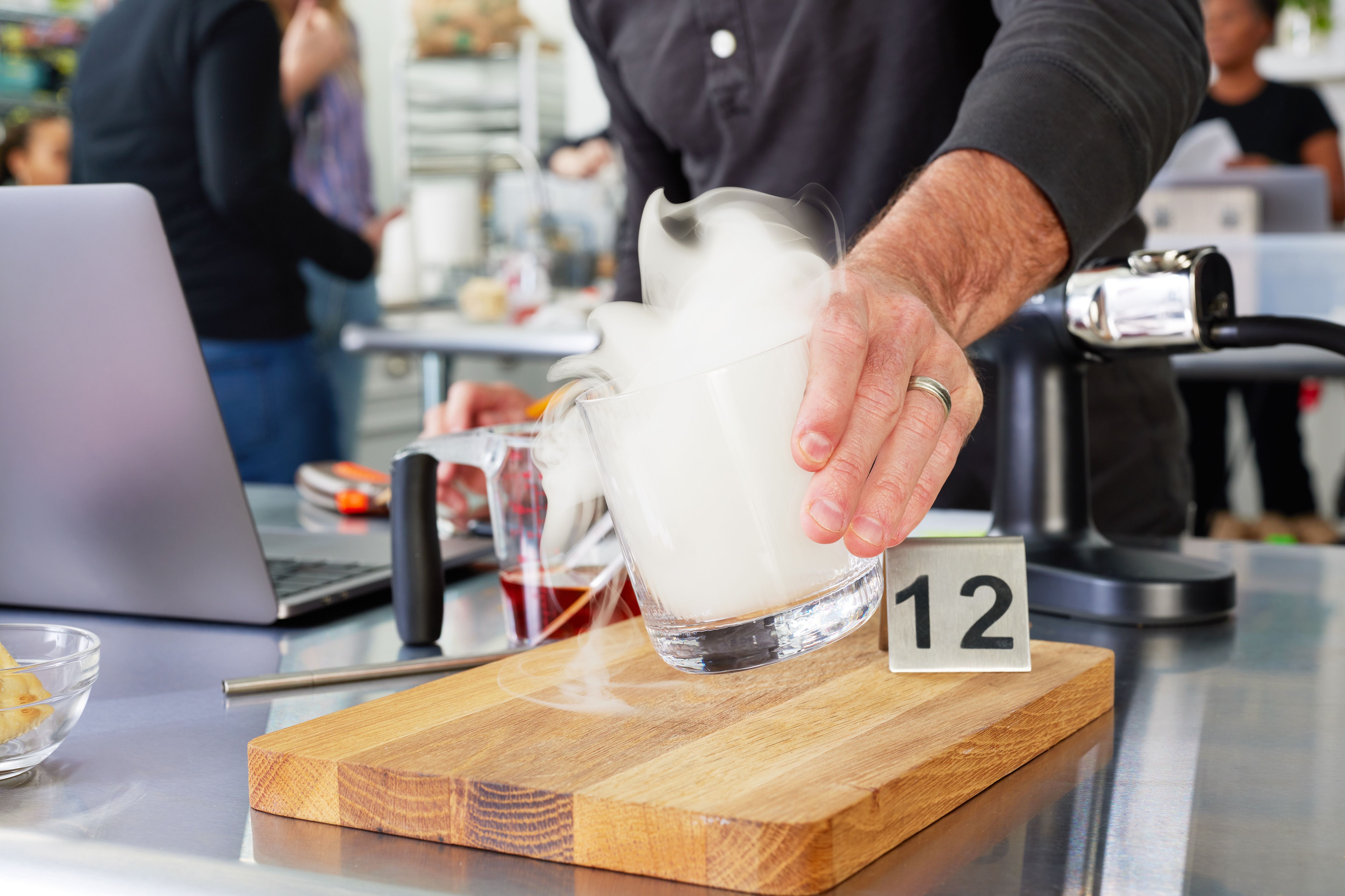 A hand holding a cocktail glass that smoke is rising out of 