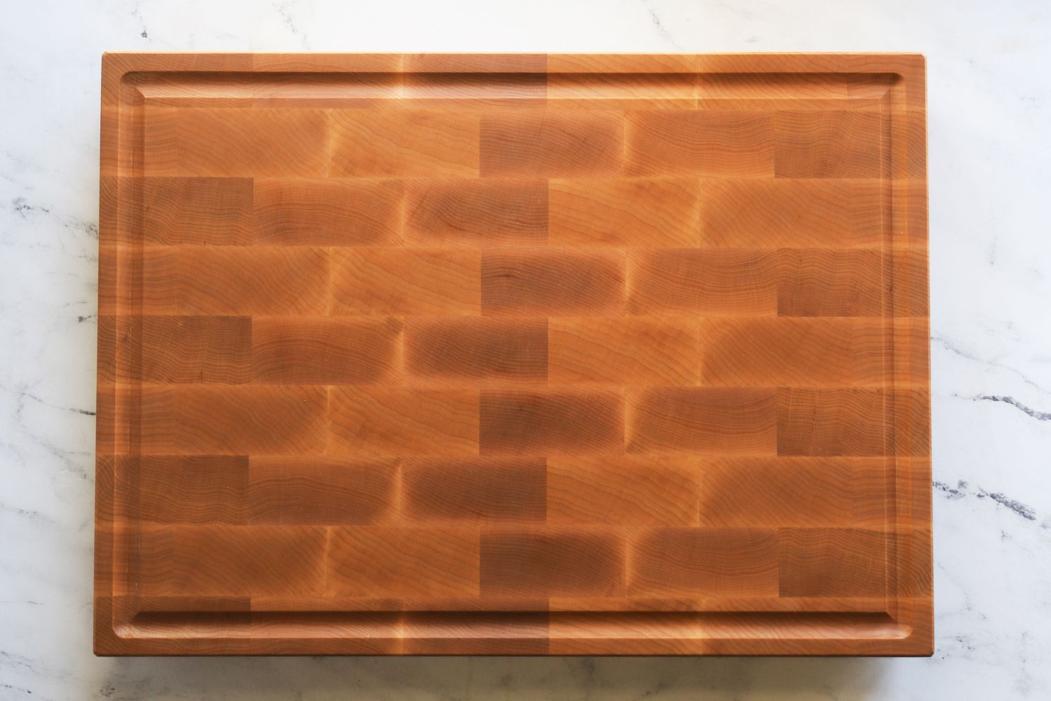 A wooden carving board on a marble surface