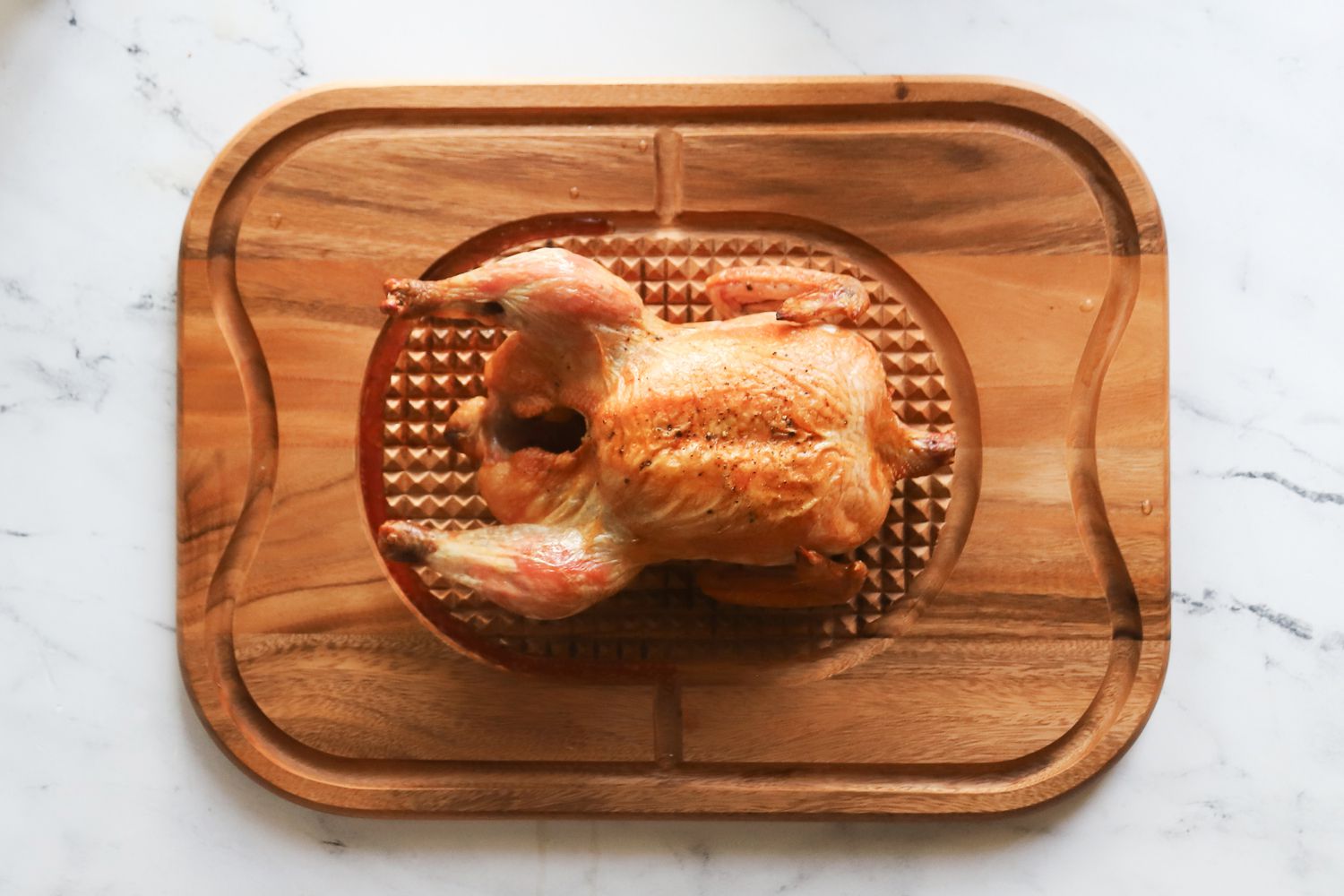 a roast chicken sitting in the center of a wooden carving board
