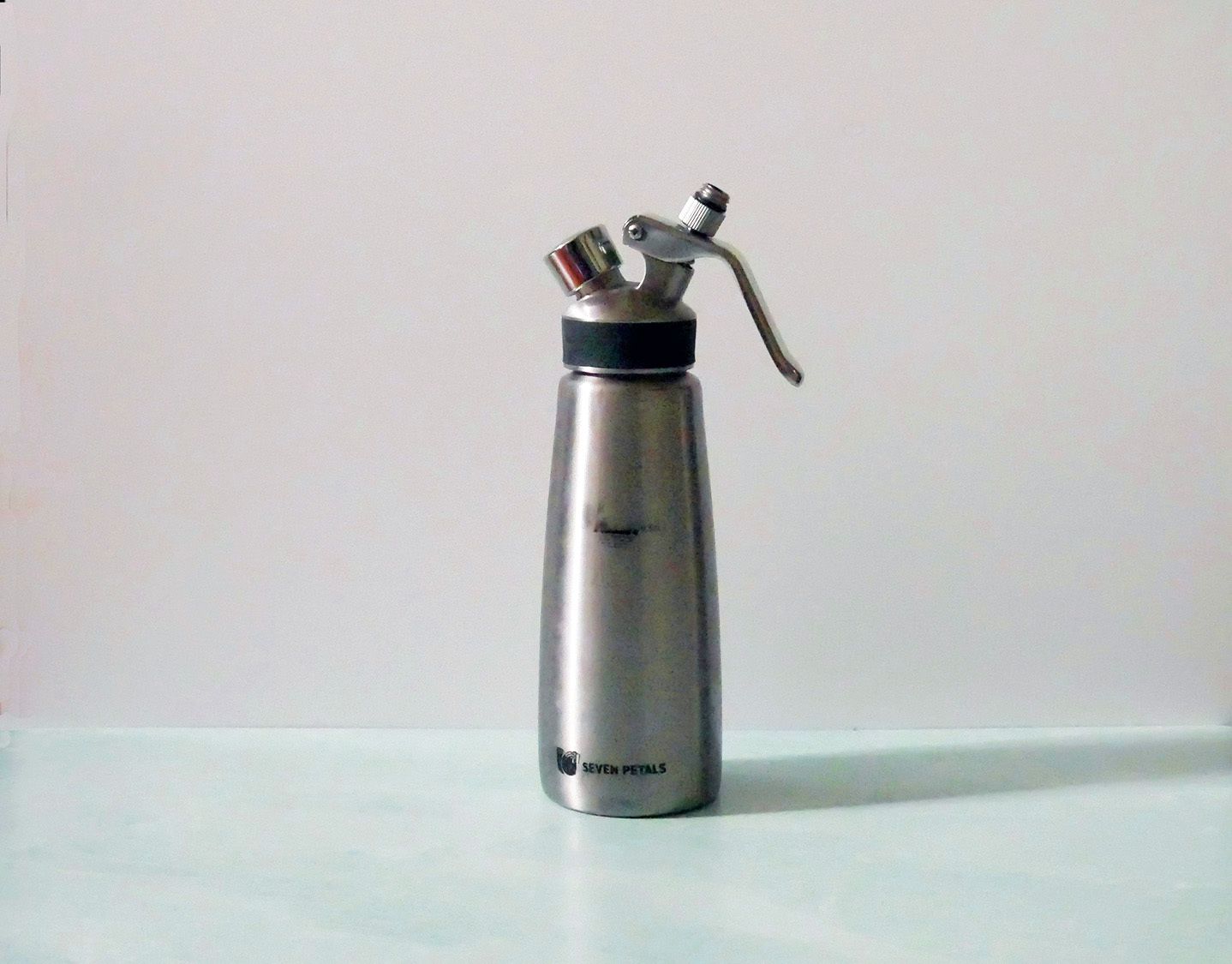 a stainless steel siphon on a blue countertop