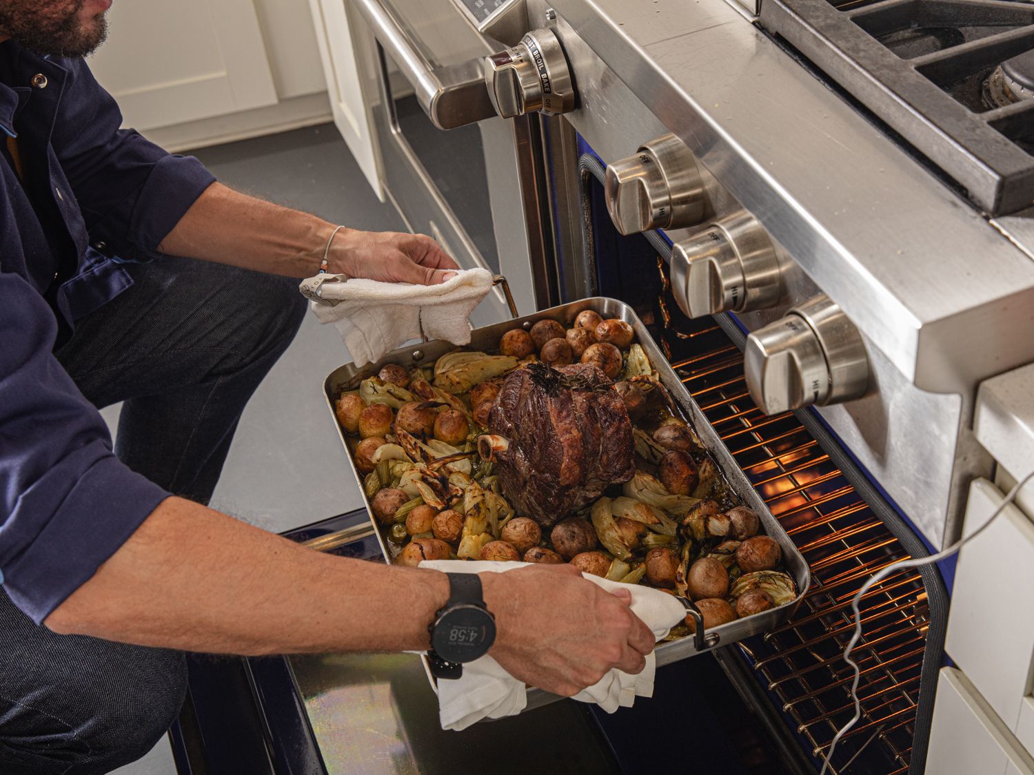 a person putting a full roasting pan into the oven