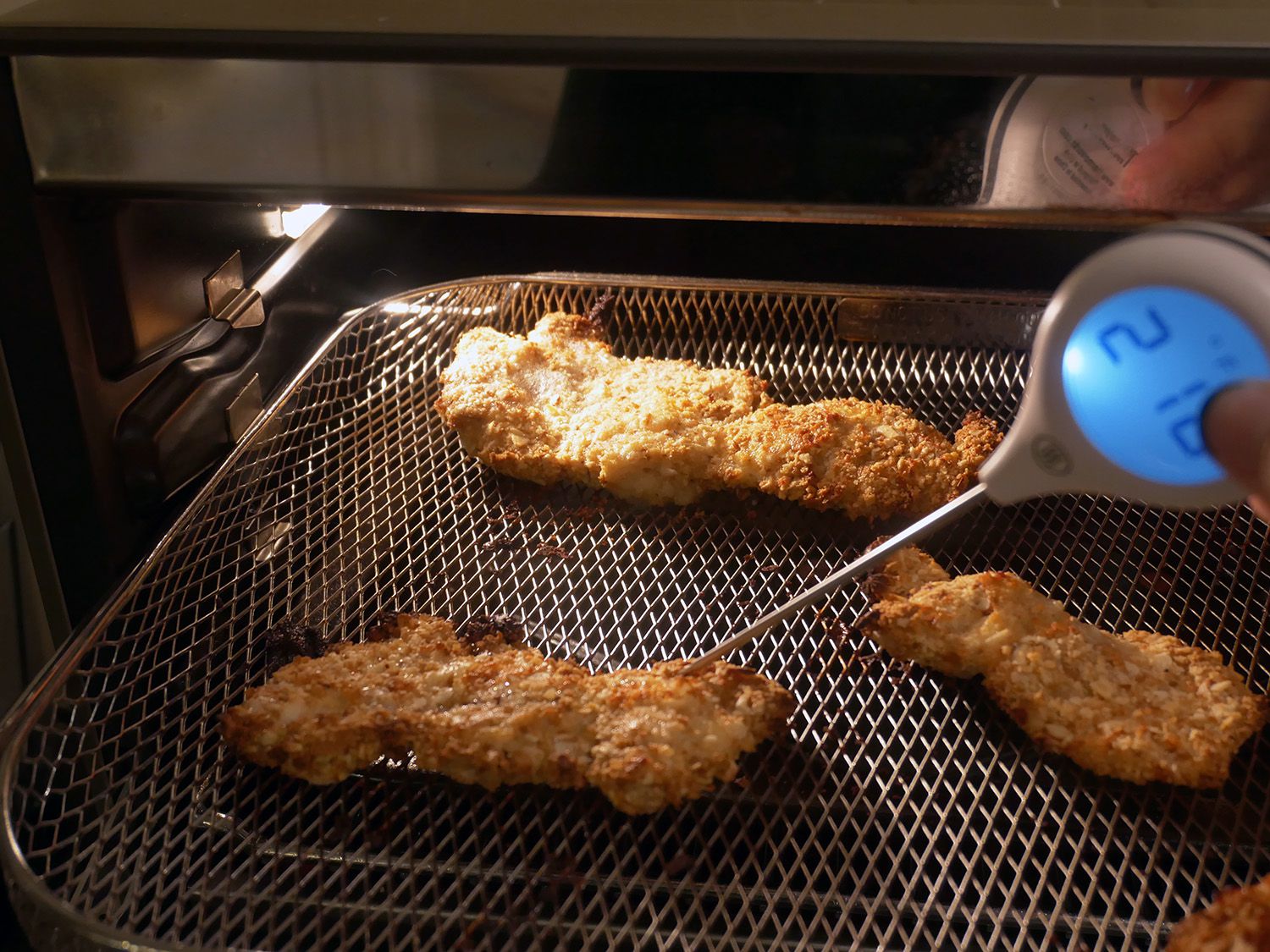 crispy chicken cutlets in breville, with hand taking temperature with thermometer