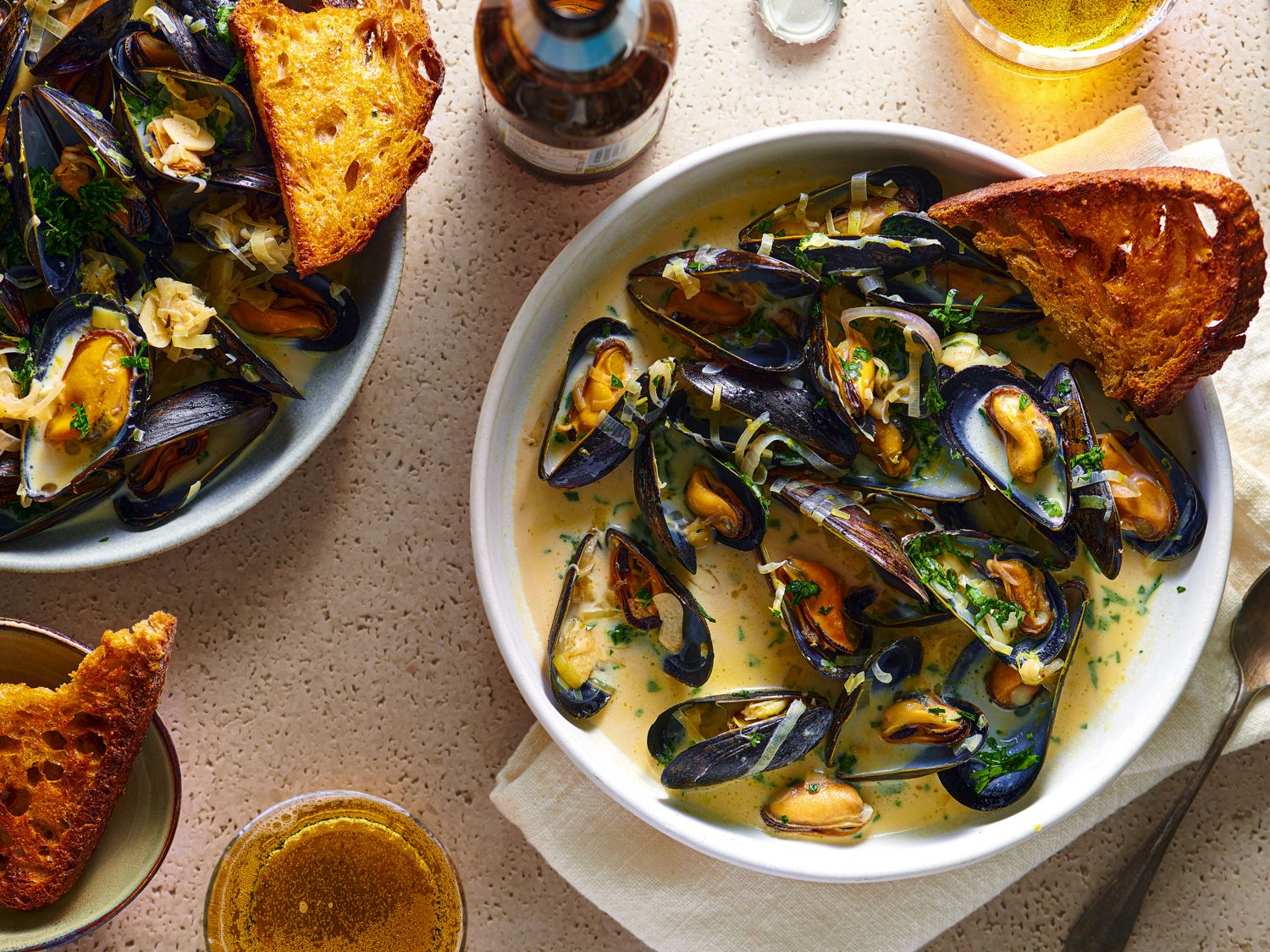 A bowl of moules marinieres with a piece of bread in it.