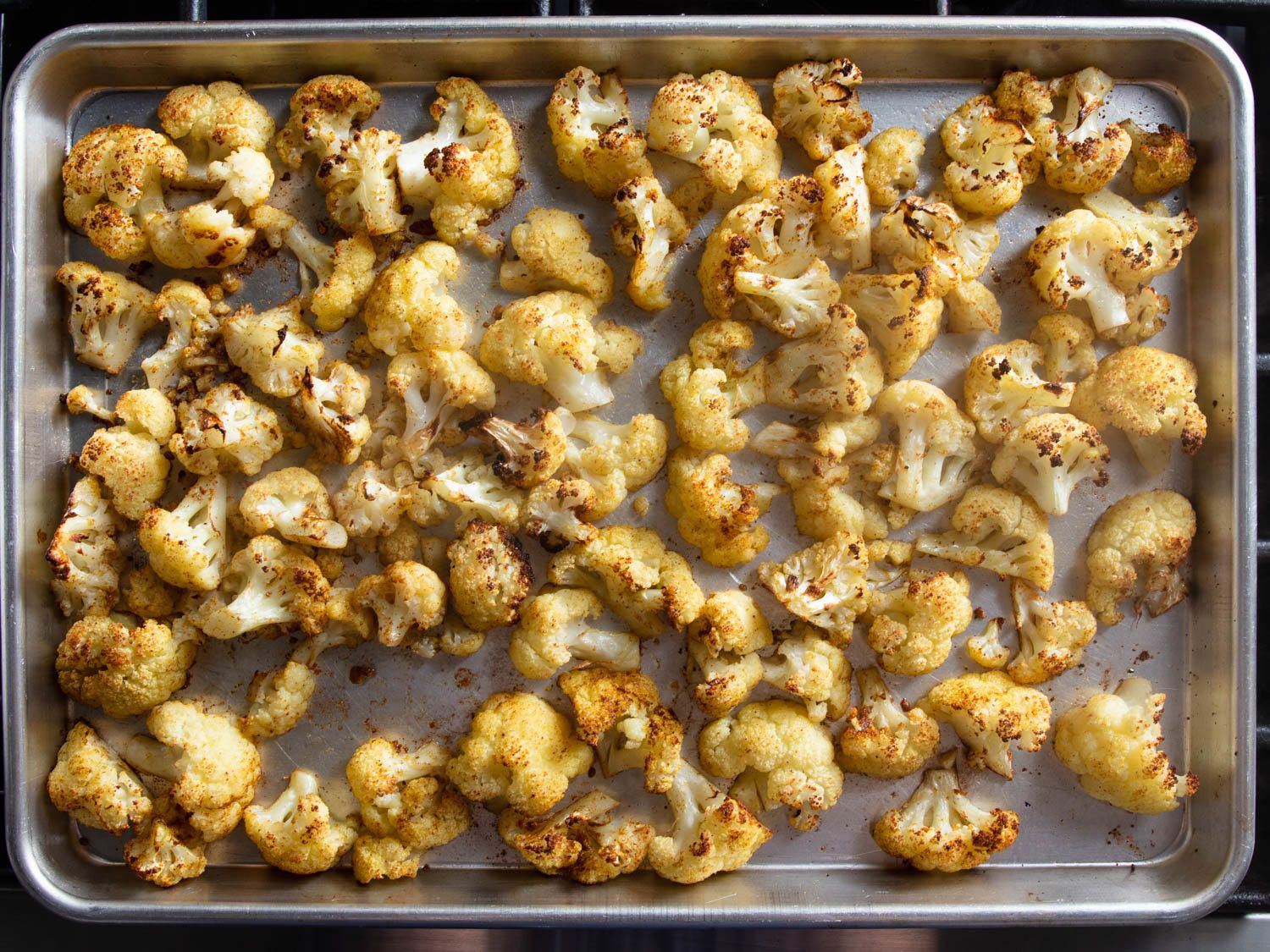 Roasted cauliflower florets on a rimmed baking sheet