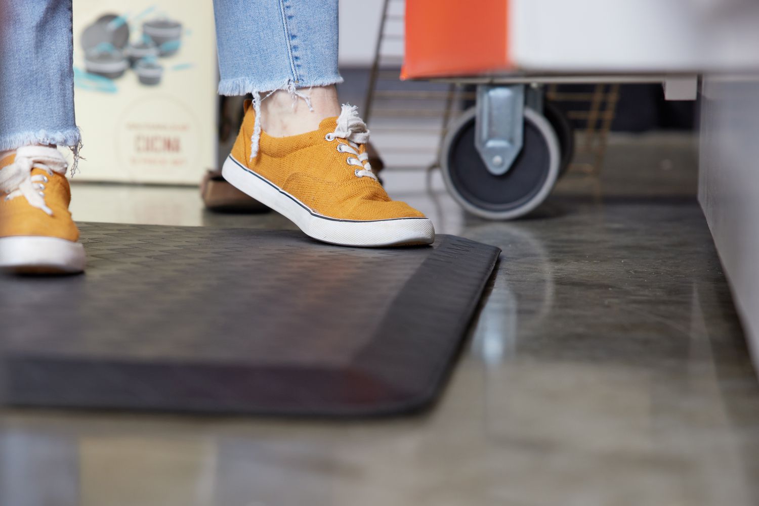A closeup person standing on a black anti-fatigue mat