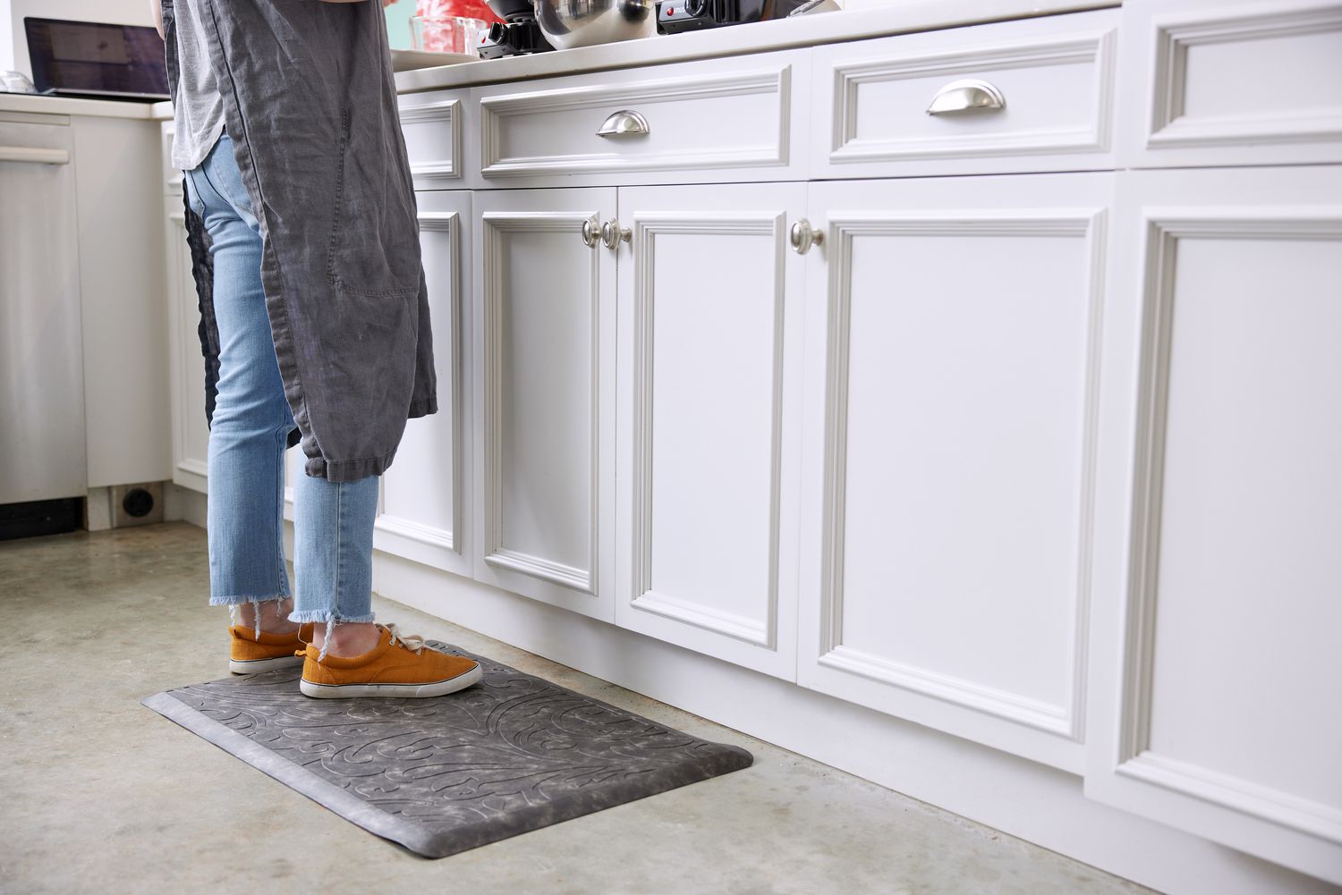 A person standing on an anti-fatigue mat at a kitchen counter