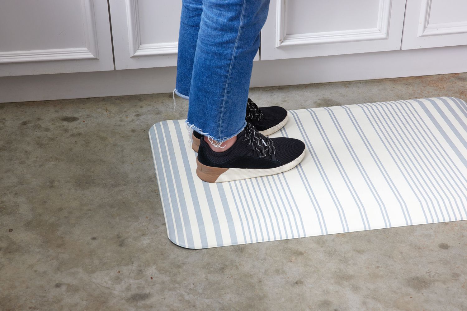 two legs standing on a blue and white striped kitchen mat