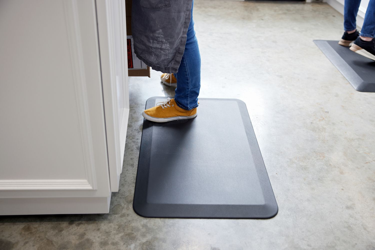 a person standing on a black anti-fatigue mat in a kitchen