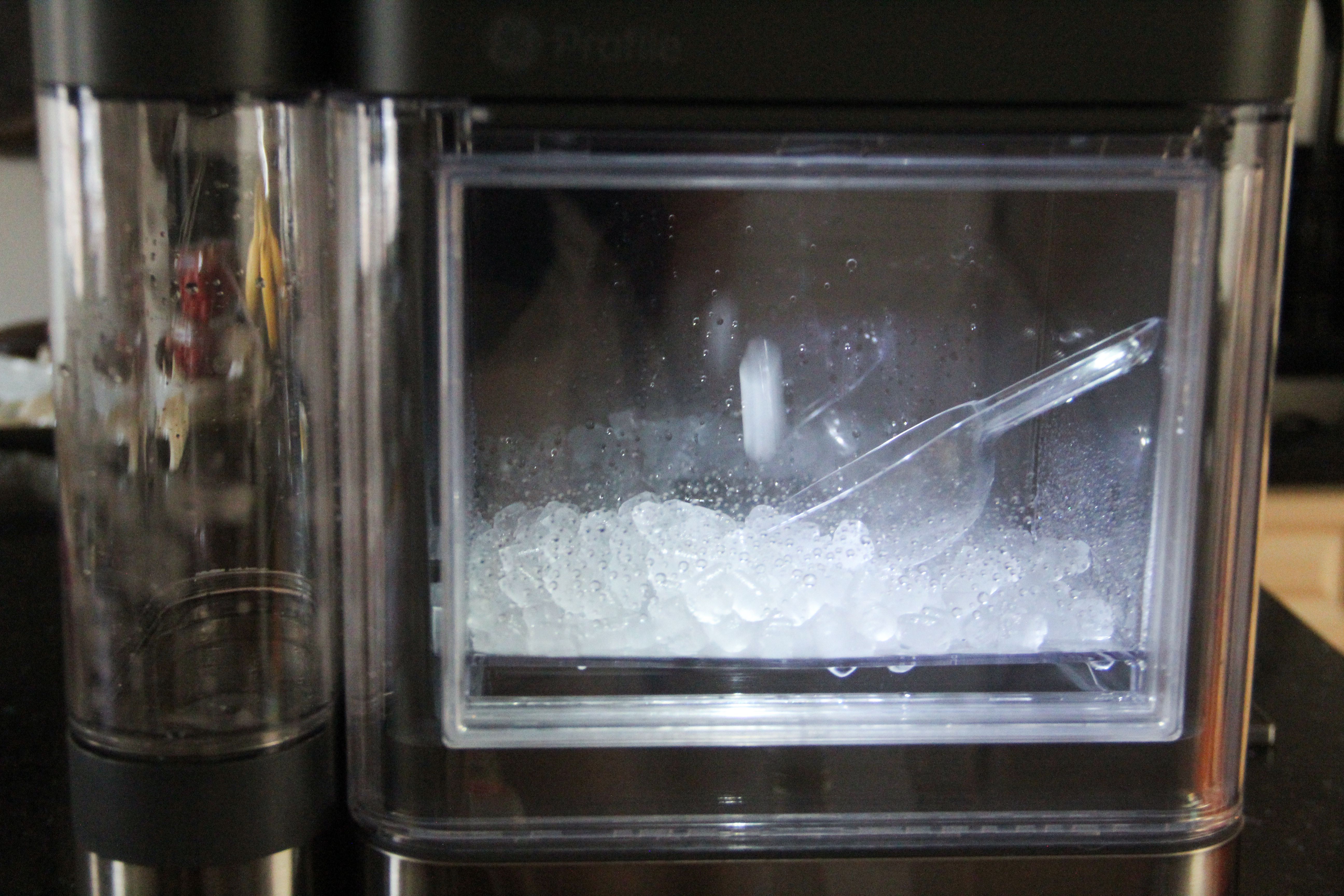 ice maker box with ice and ice scoop inside.