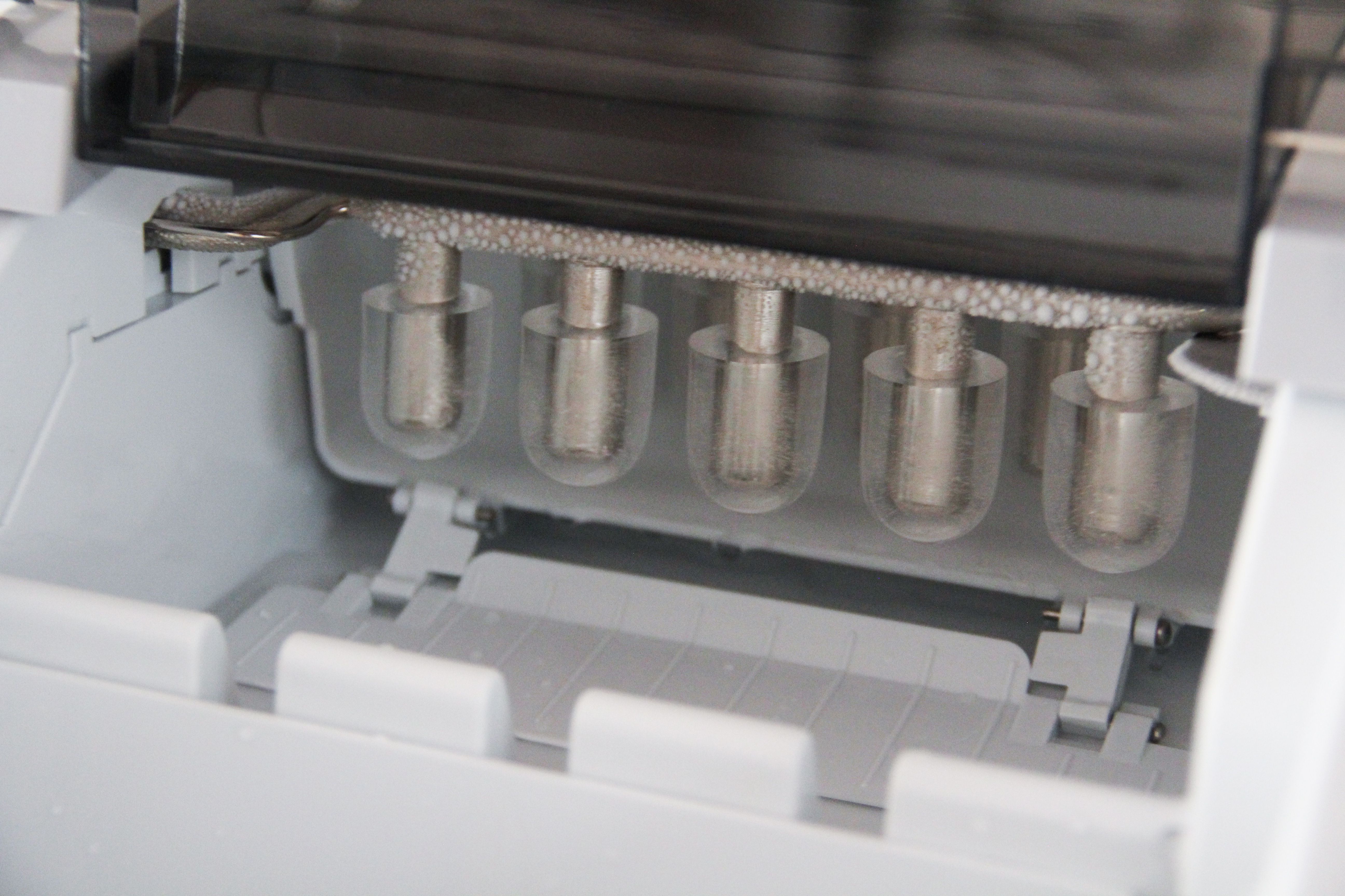 the interior of one ice maker with ice on the prongs.