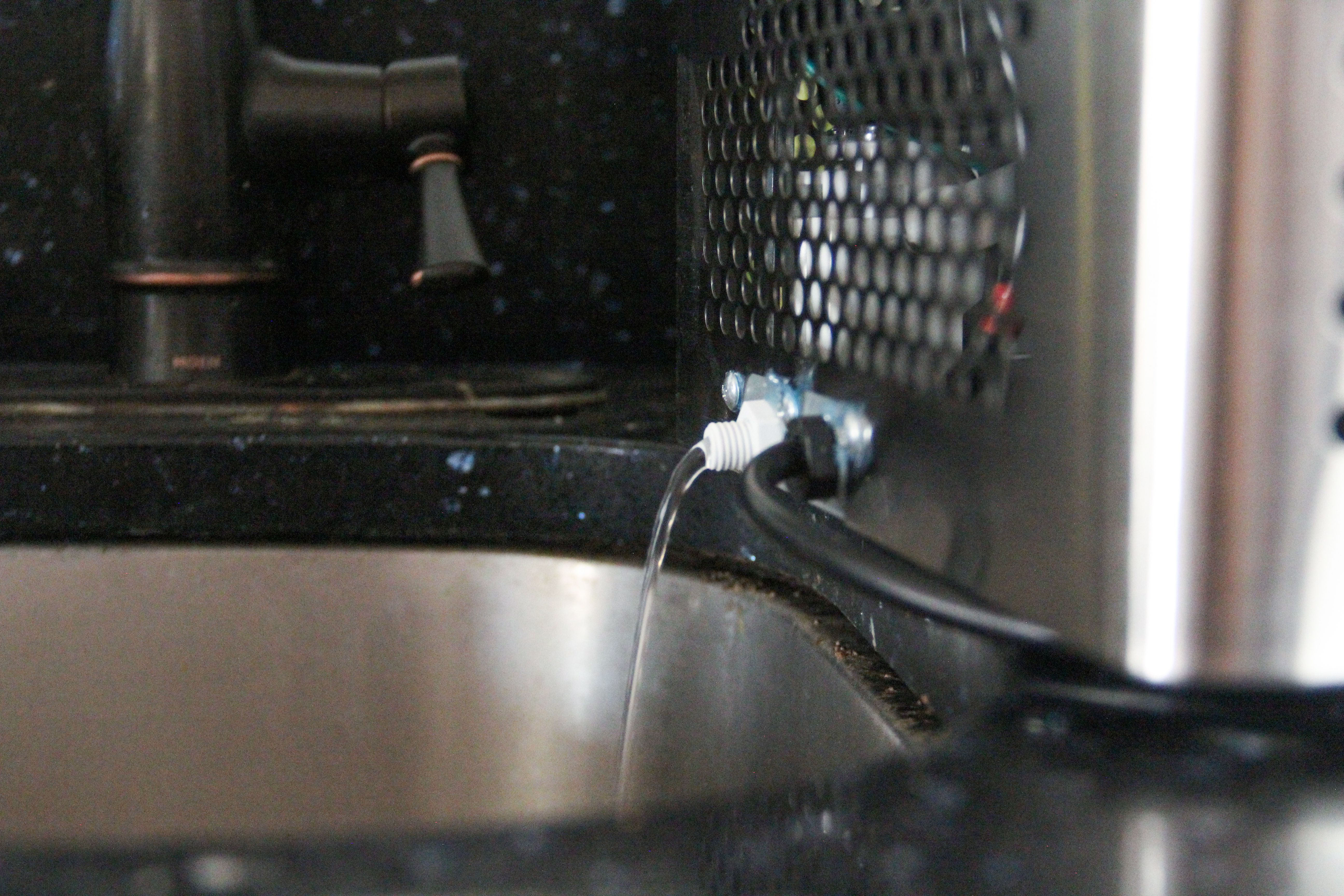 the spout of the Luma ice machine with water coming out of it and pouring into the sink