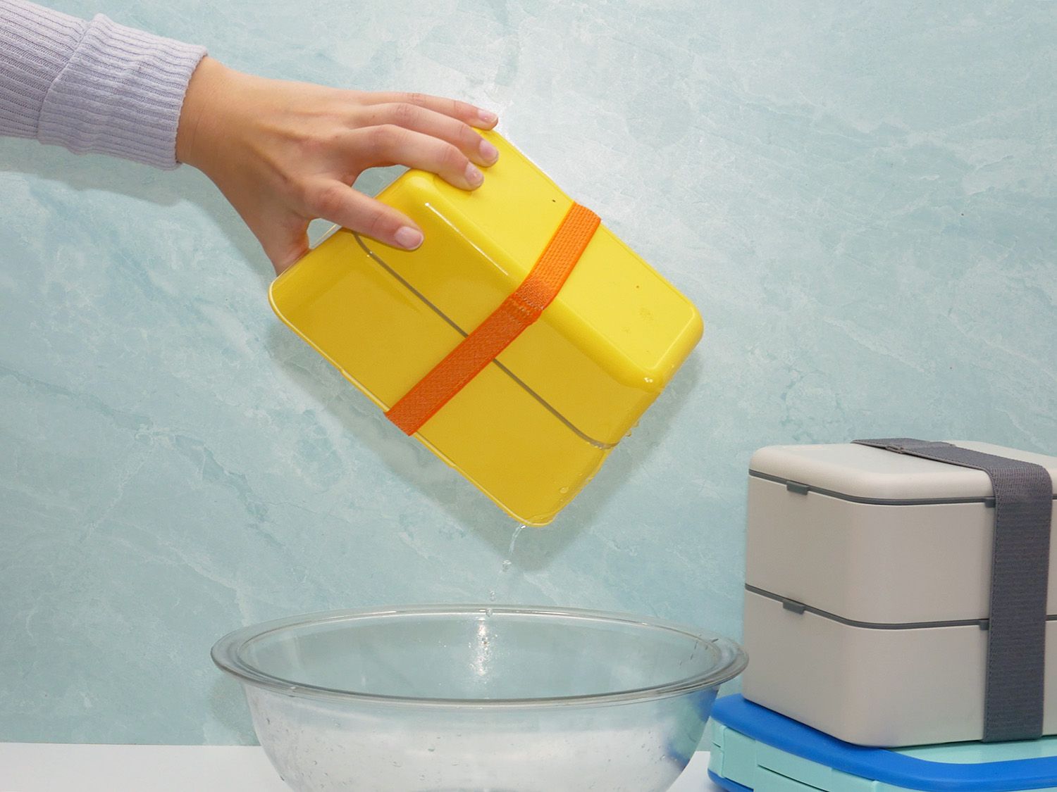 shaking a bento box with water over a bowl.