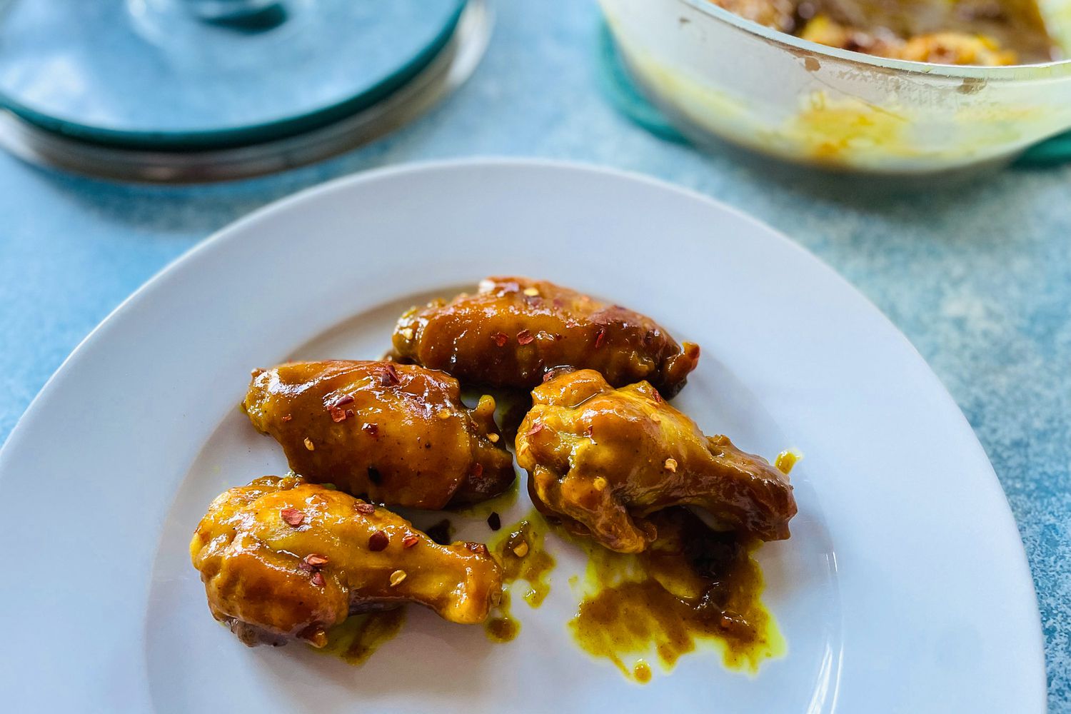 A plate of chicken wings with an Anyday dish full of chicken wings behind it