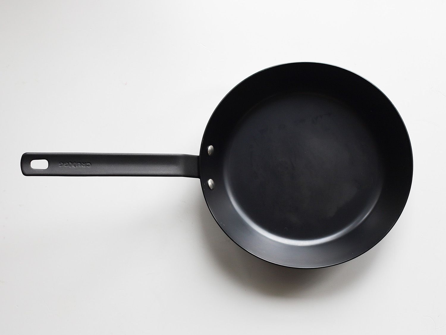 cruxxgg carbon steel skillet on a white surface