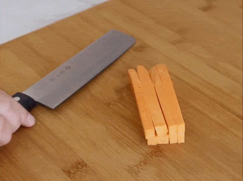 A video of a person using a nakiri knife to cut a sweet potato on a wooden cutting board