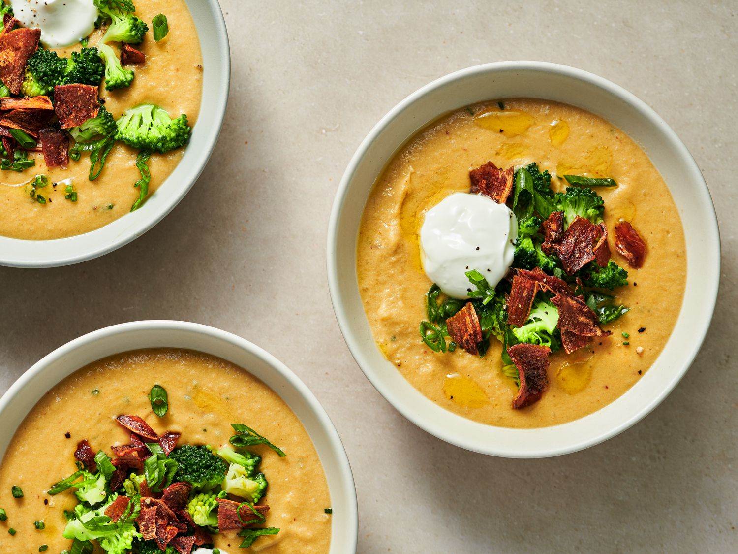 Three bowls of fully loaded vegan baked potato soup.