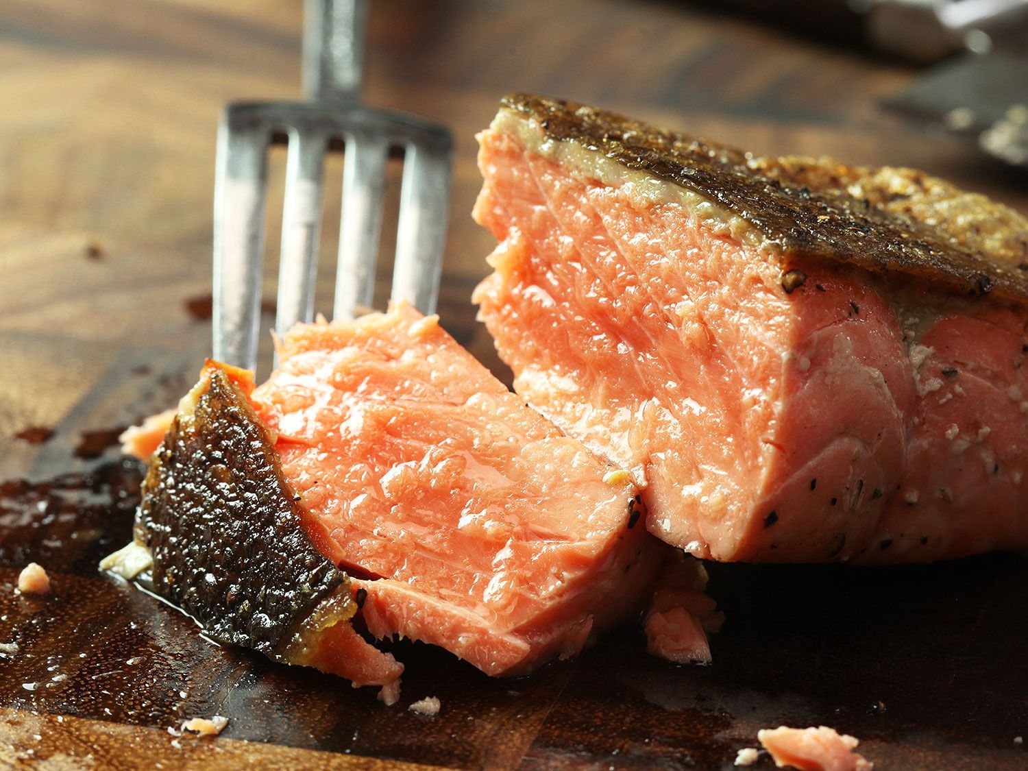 Fork digging into a portion of pan-seared salmon
