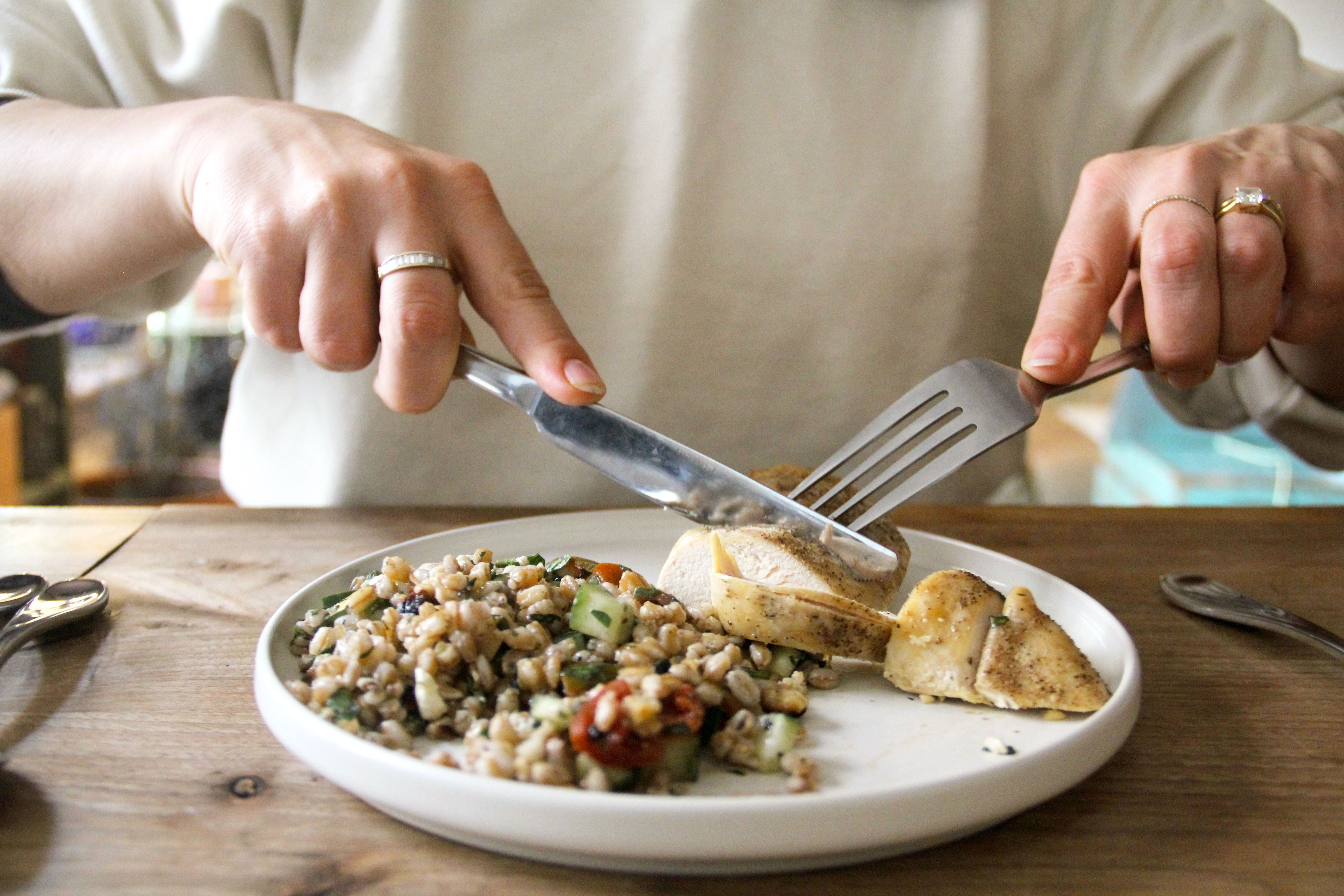 a person using a fork and knife to slice through chicken breast on a plate