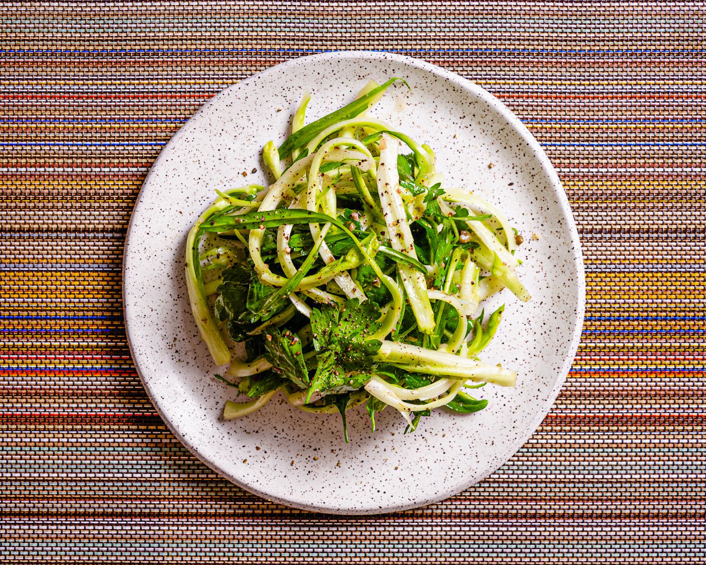 Overhead view of puntarelle salad on a colorful stripped background