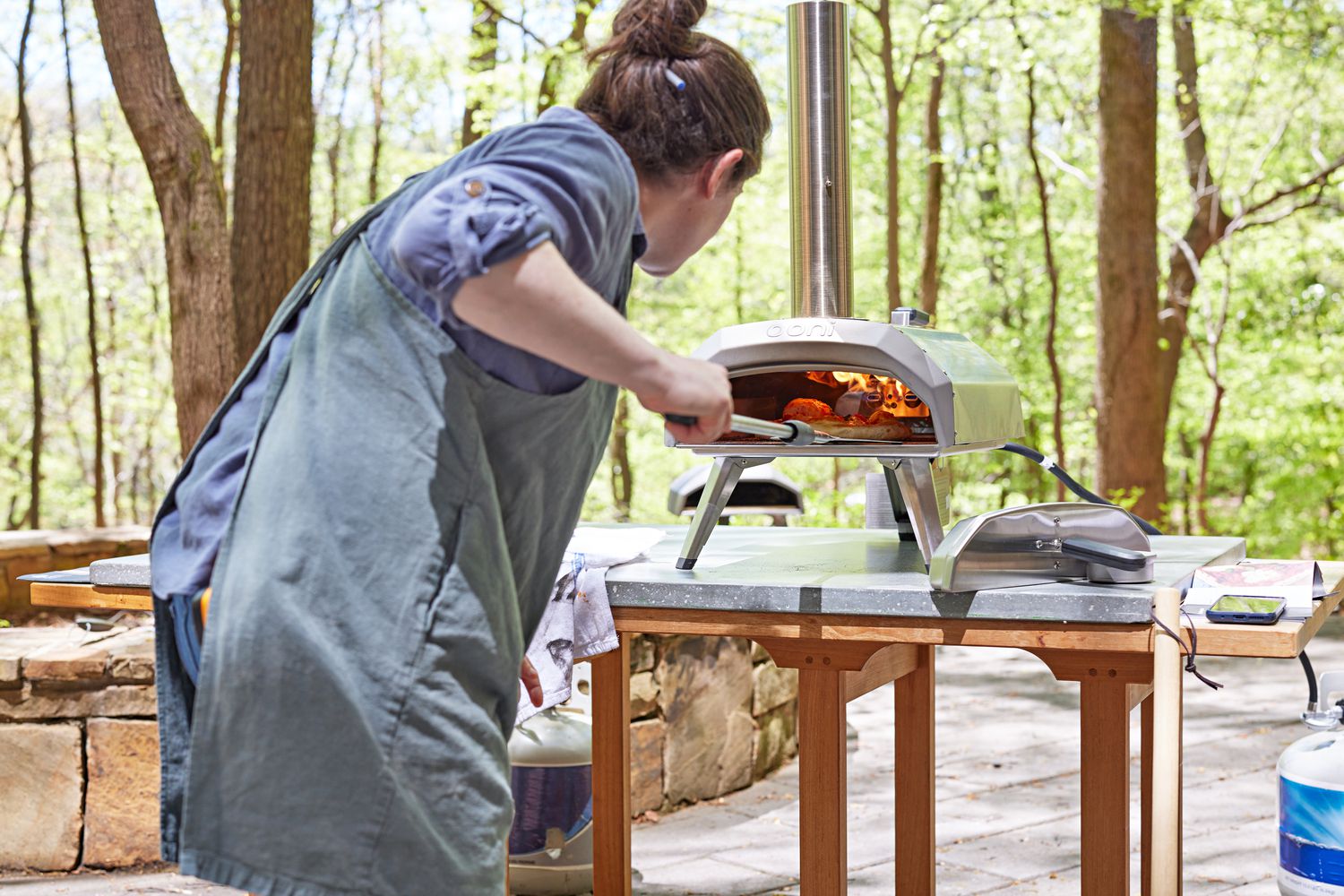 a person turning a pizza in the Ooni Karu 12