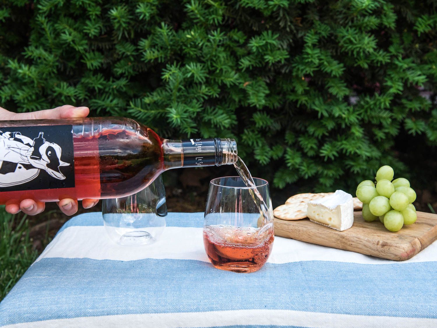 a person pouring rose into a wine glass
