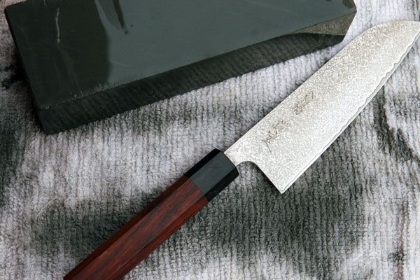 a knife next to a whetstone on a towel