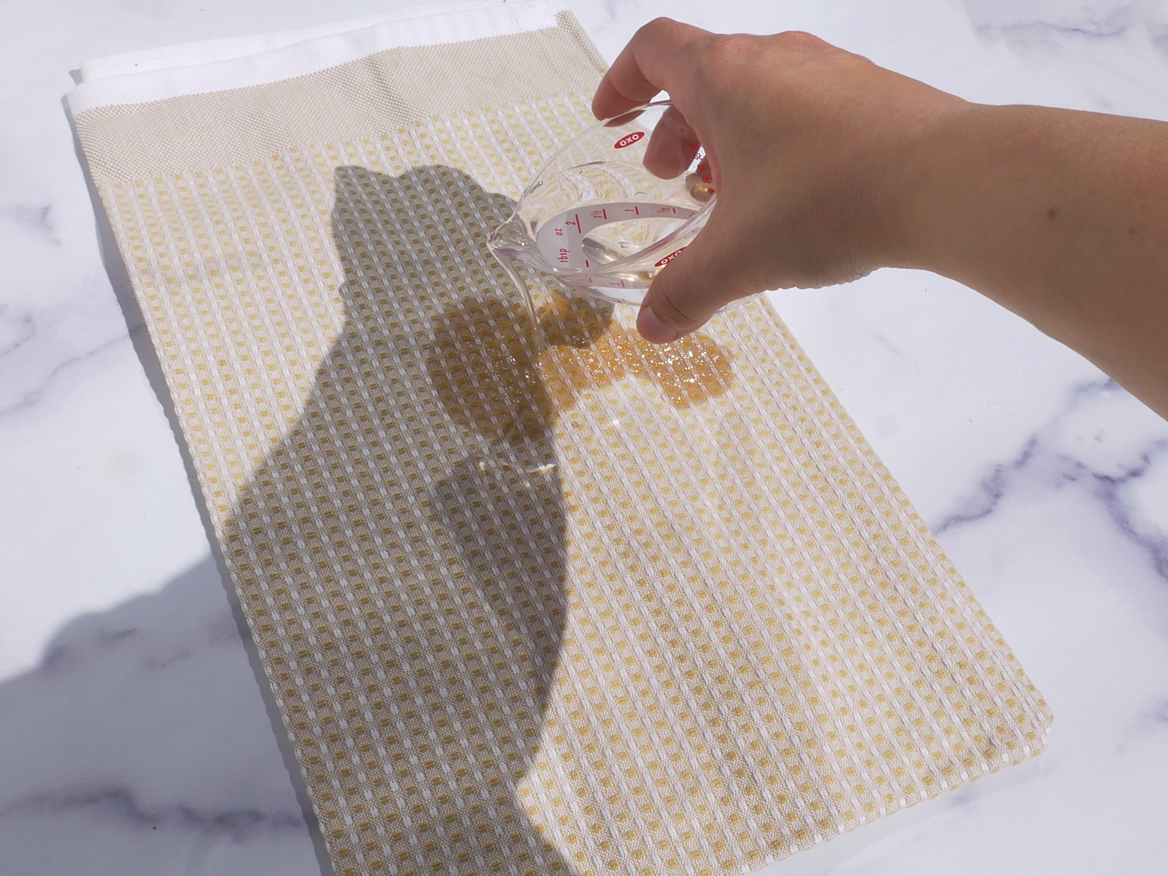 A hand pouring water onto a dish cloth