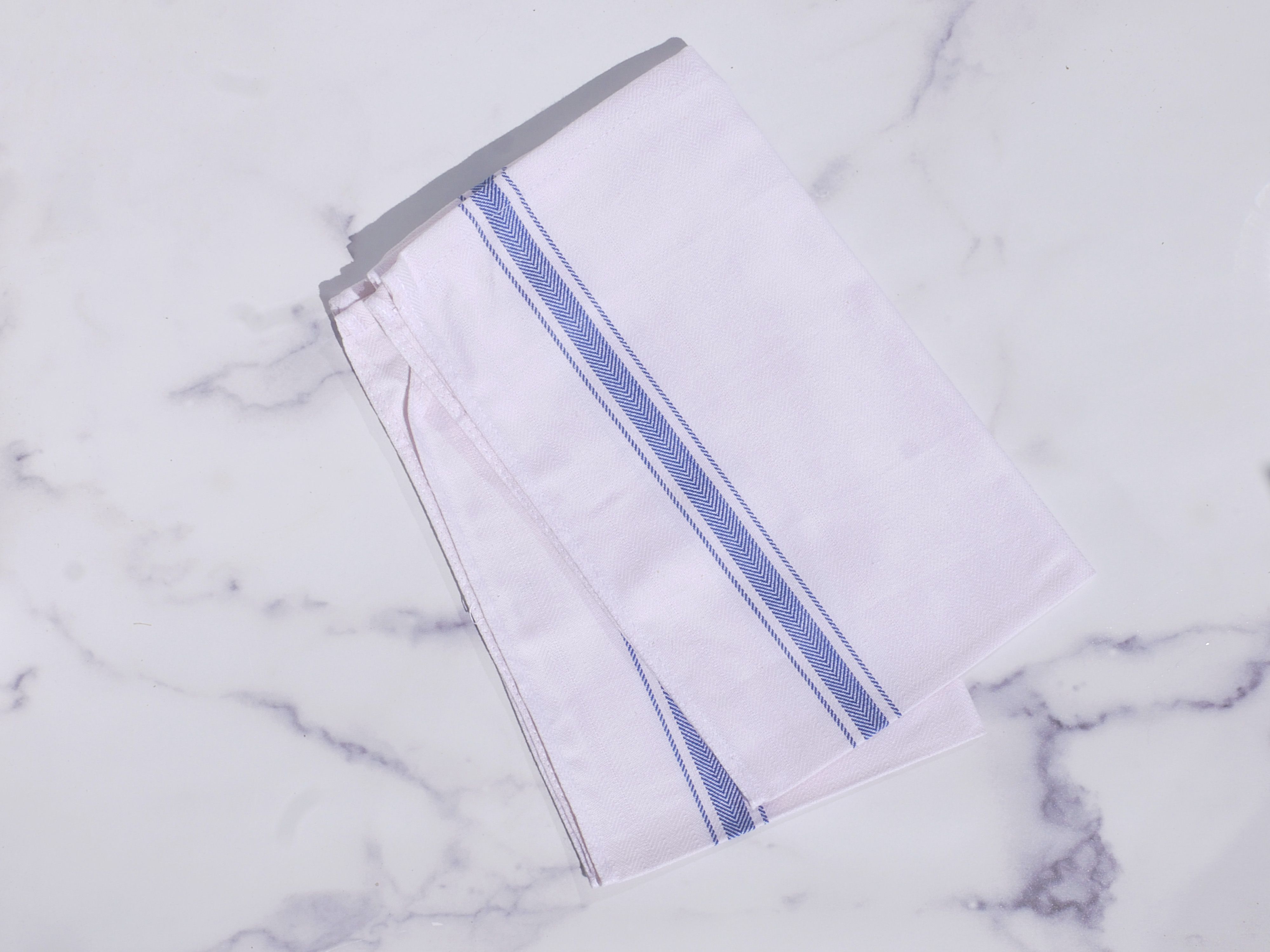 A blue and white dish towel on a marble surface