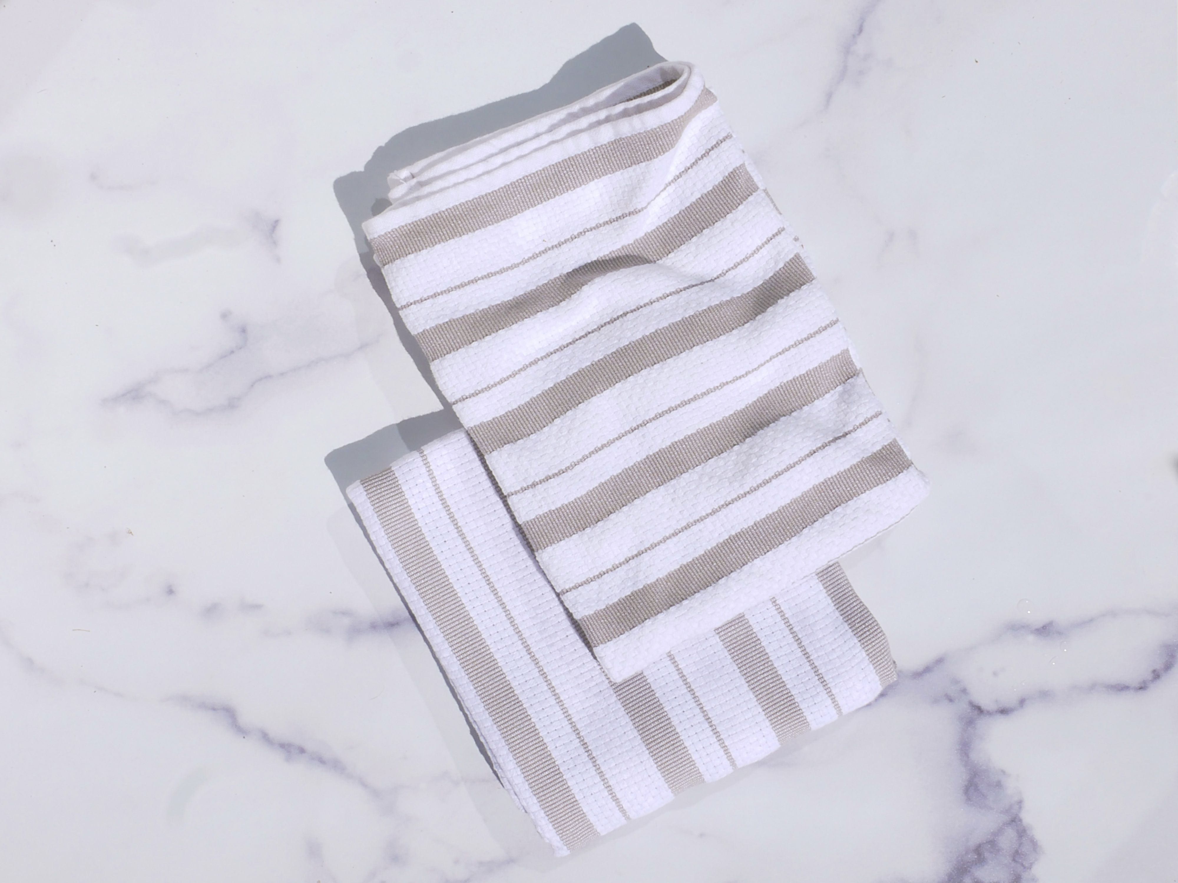 A tan and white stripped towel on a marble surface