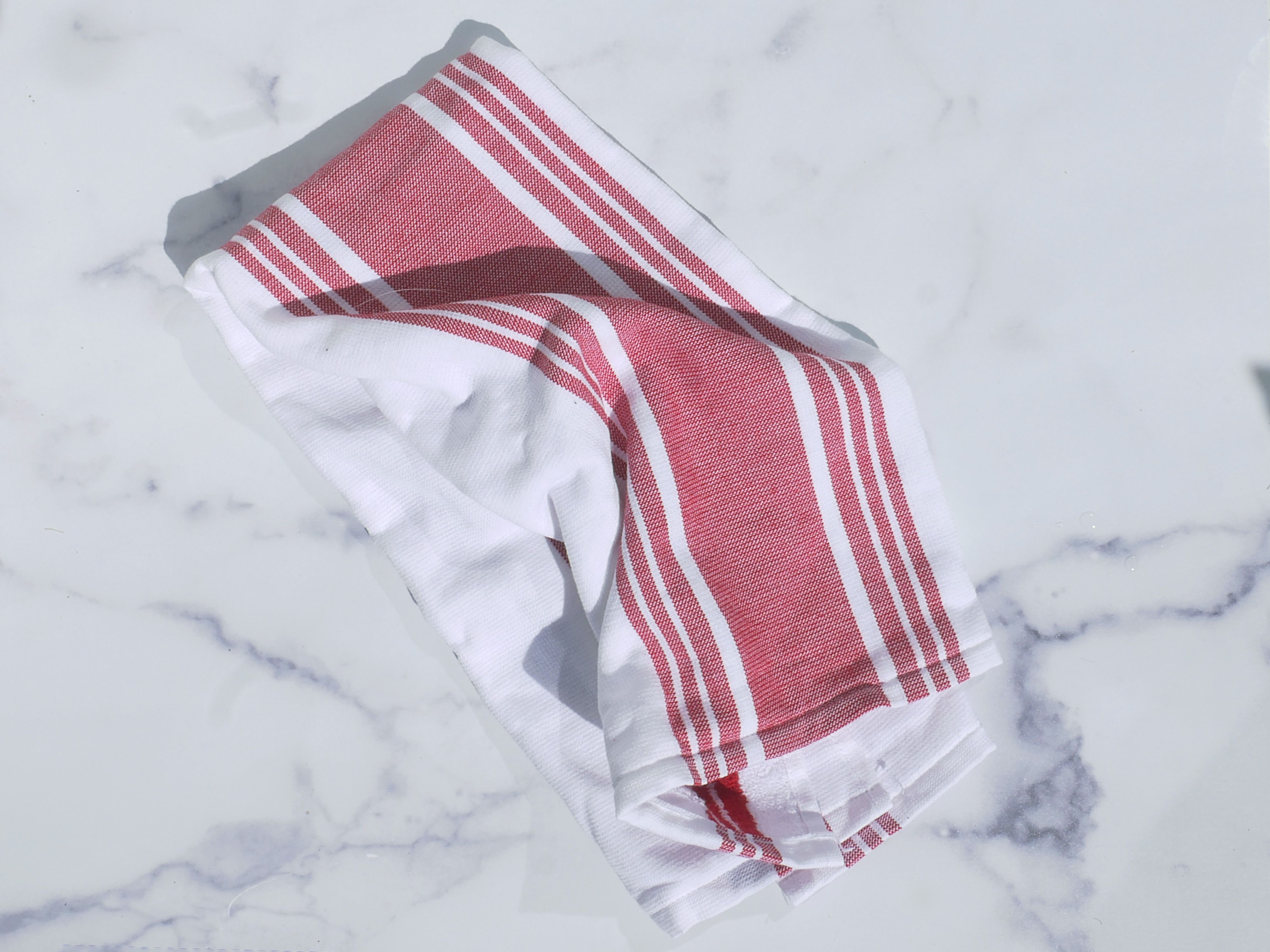 A red and white dish towel on a marble surface