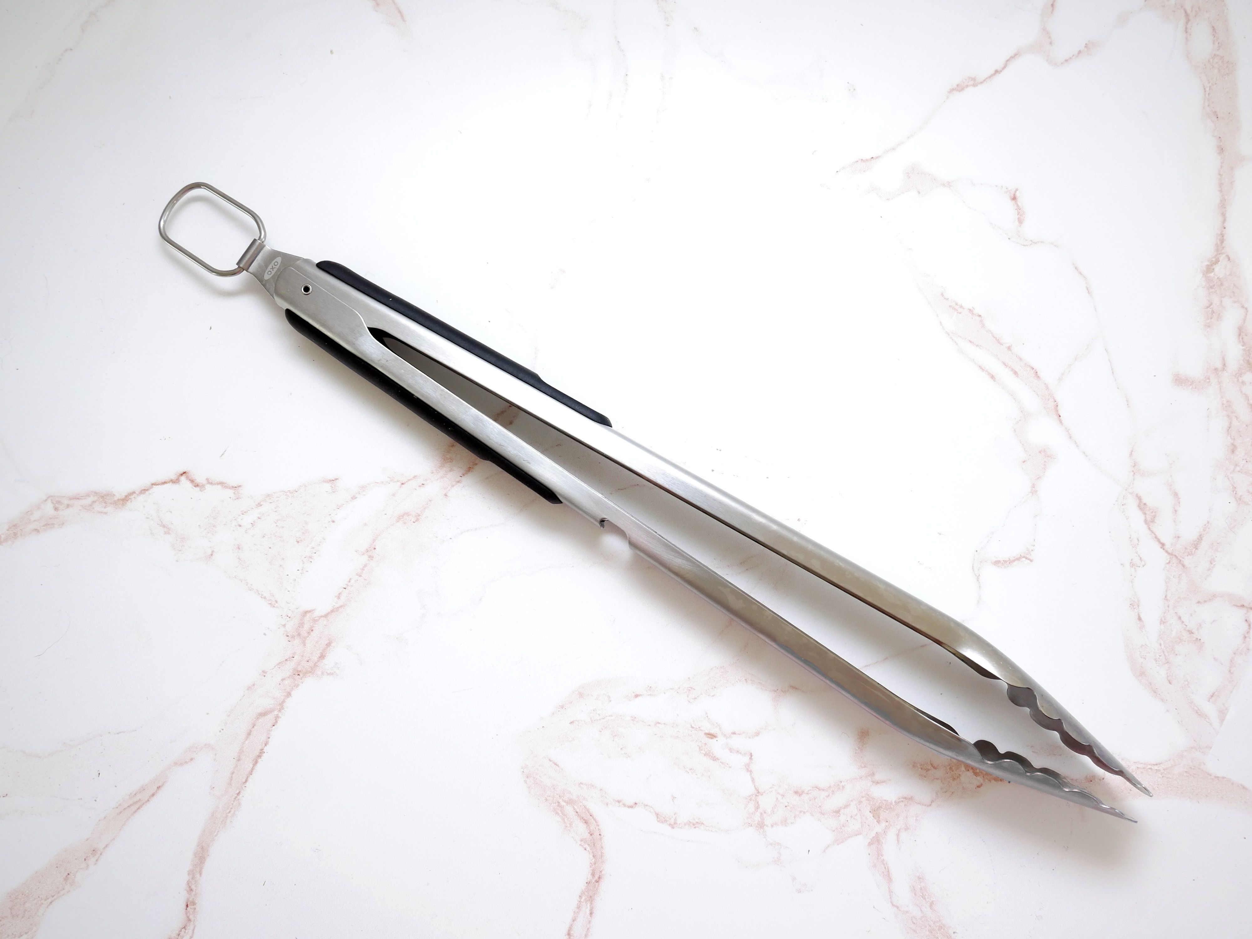OXO grill tongs on a pink and white marble surface