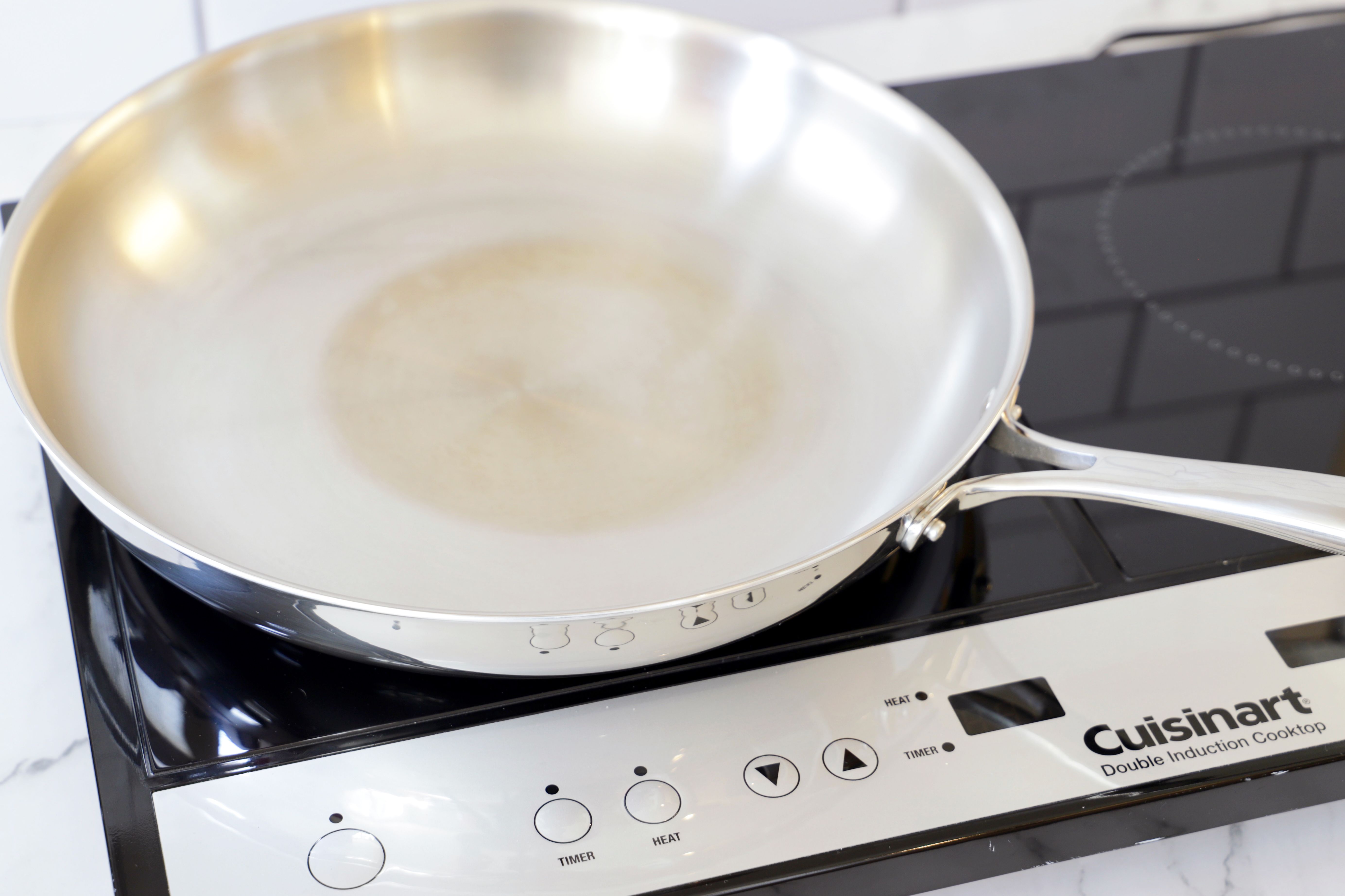 closeup of an induction burner with a stainless steel skillet on top of it