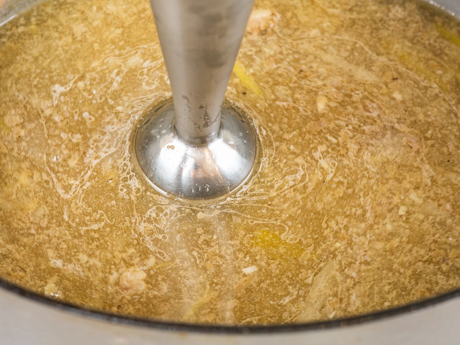 Immersion blender sunk into kare kare oxtail braising liquid