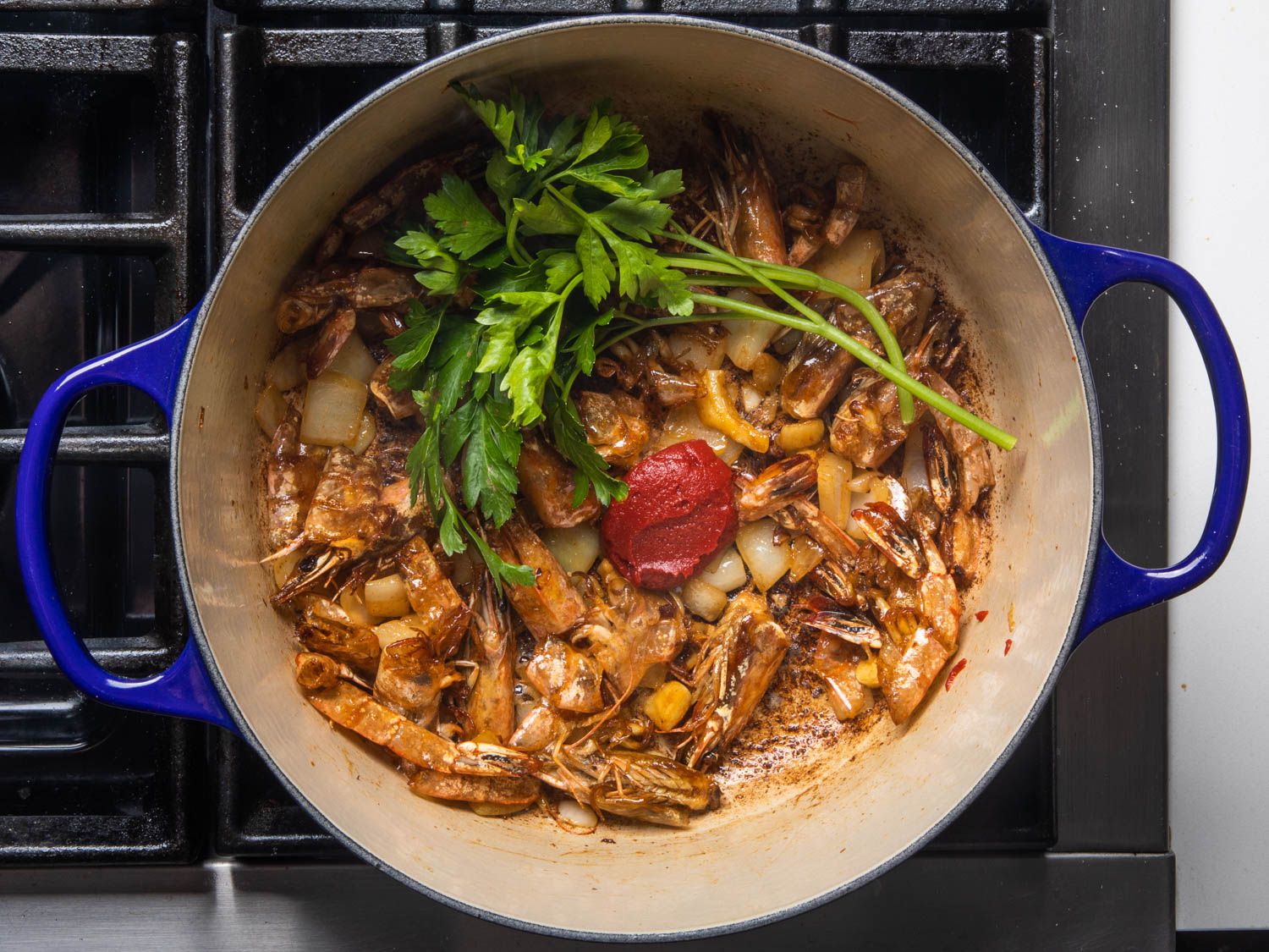 Shrimp heads and shells wit aromatics in a Dutch oven for shrimp stock.