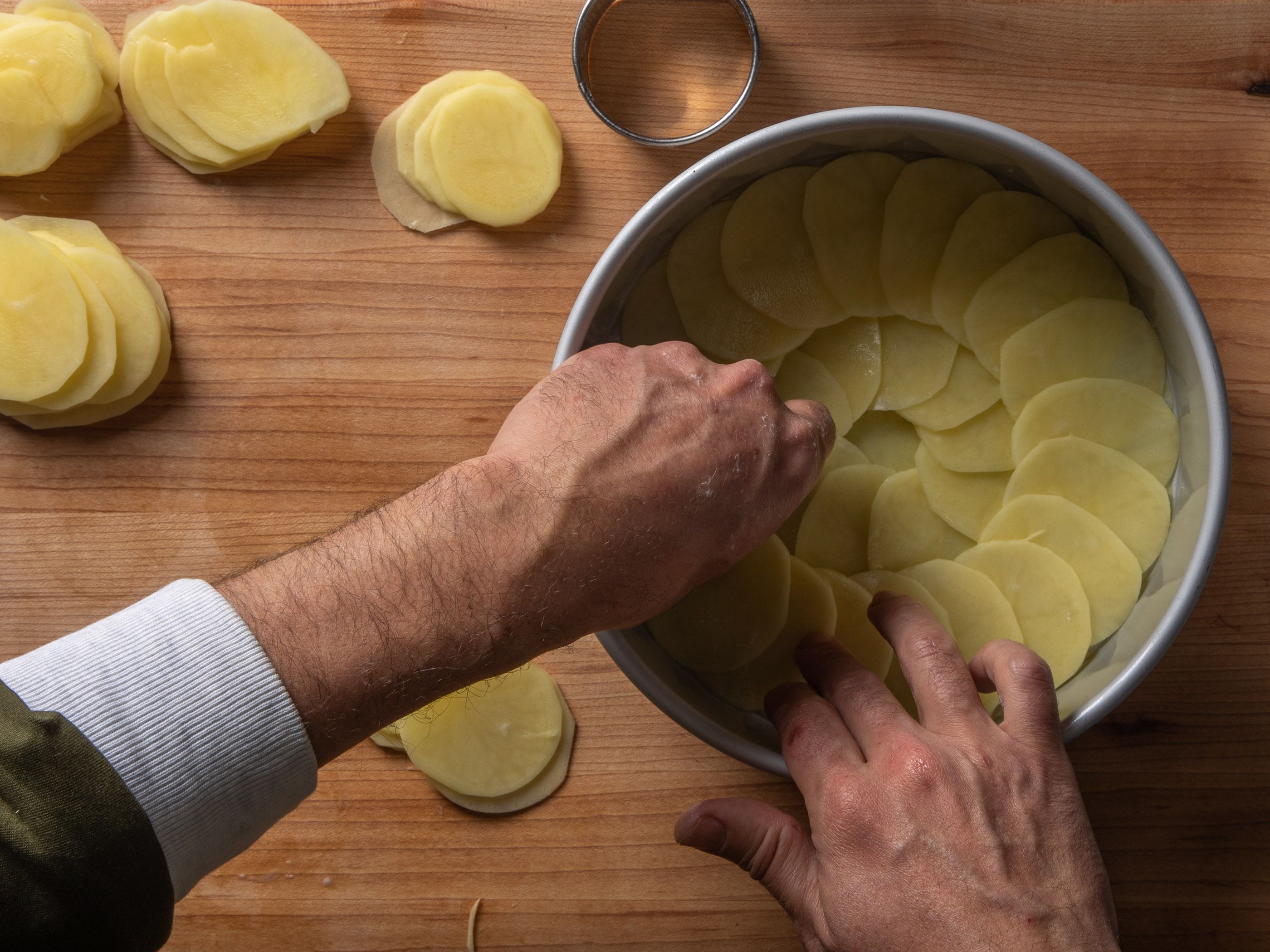 Shingling the potato slices in concentric circles from the center out.