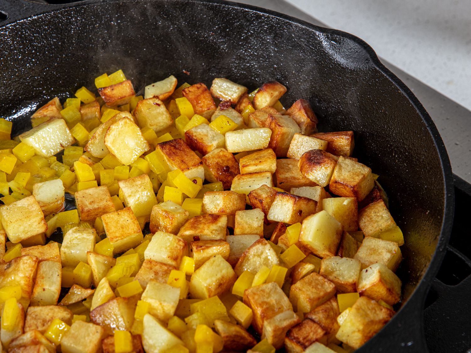 Potatoes frying in a cast iron skillet