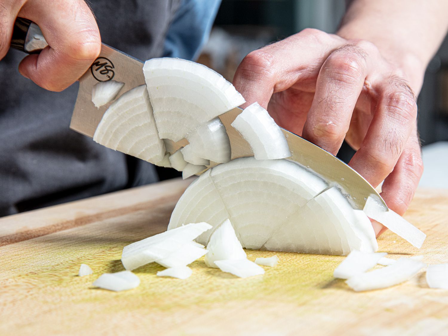 Half an onion cut in thirds being sliced.