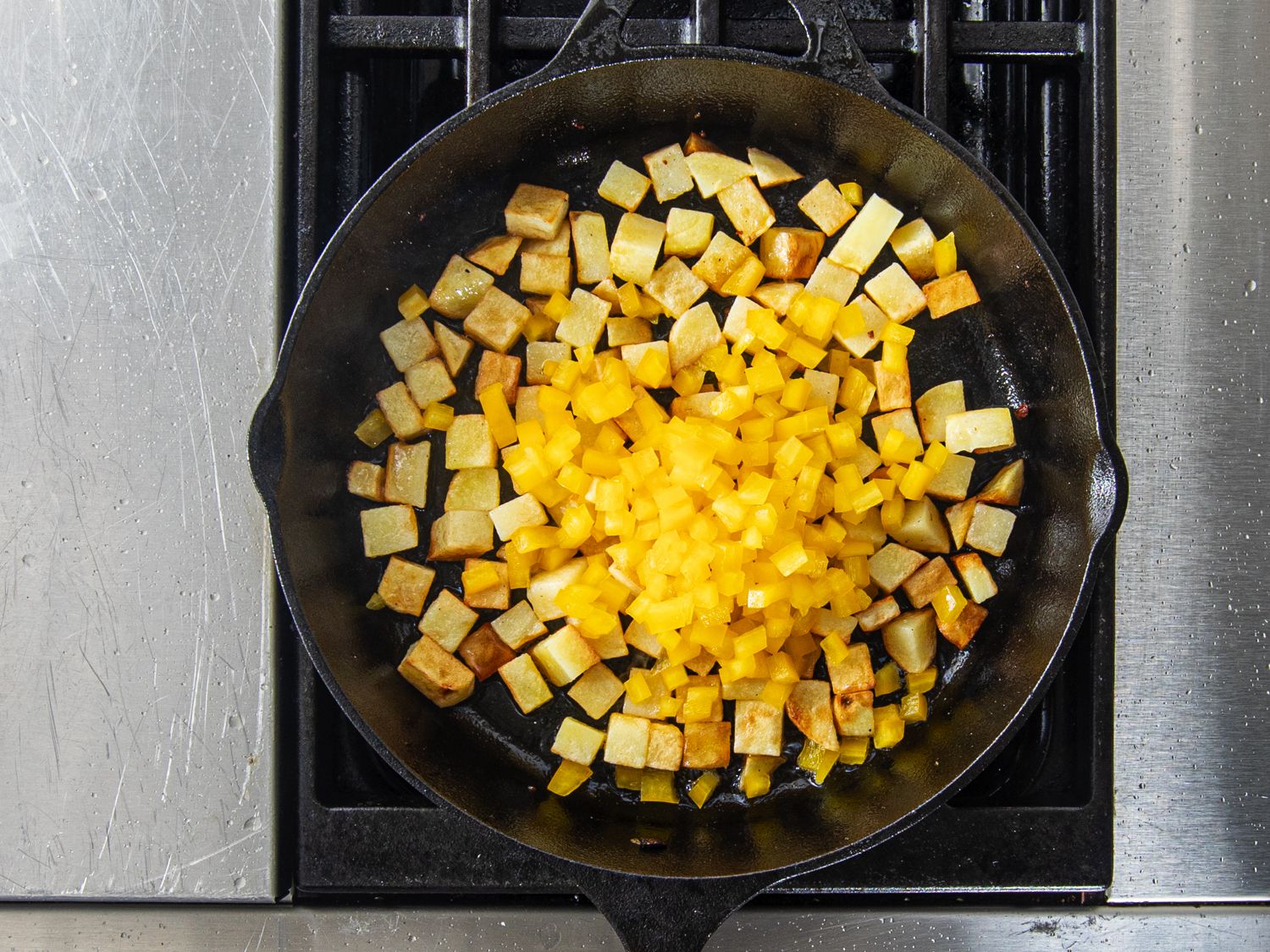 Peppers added to potatoes in skillet.