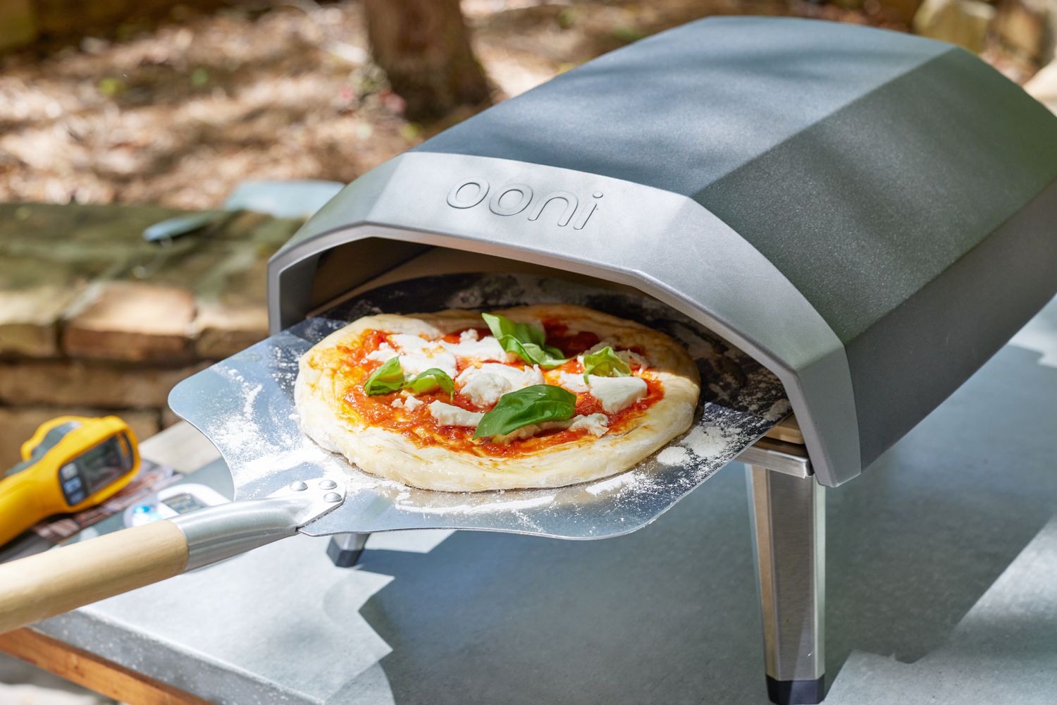 a metal pizza peel adding a pizza into the Ooni Koda 12