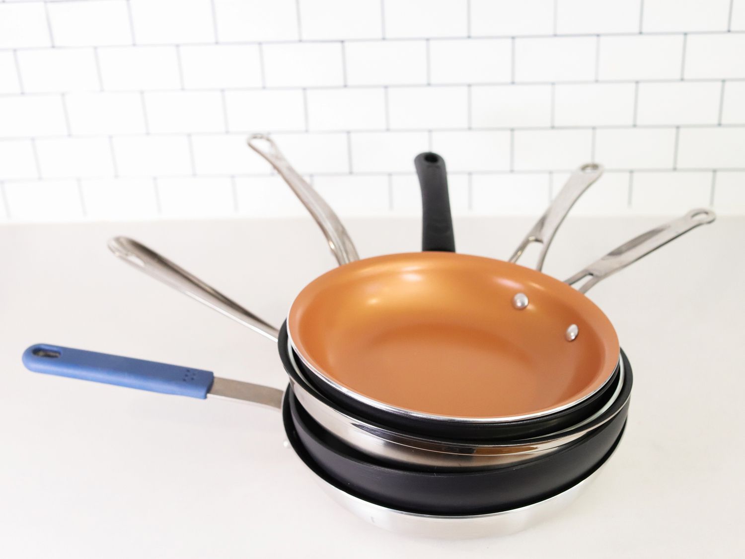 a stack of nonstick skillets sitting on a white countertop