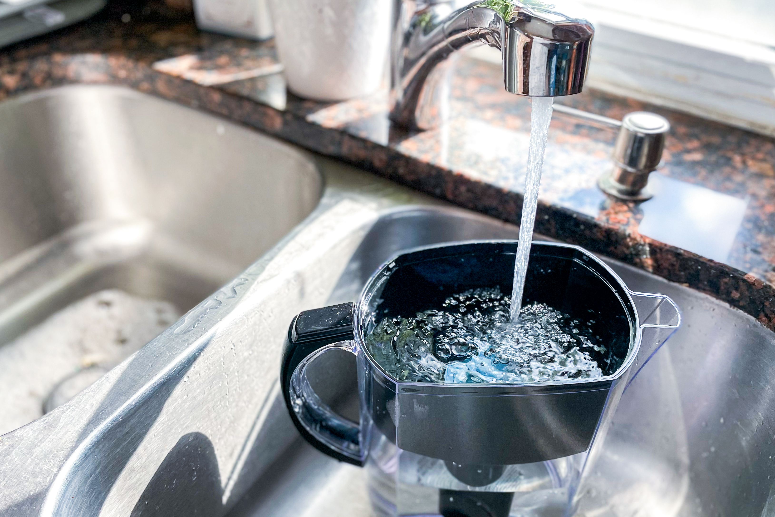 Filling the brita pitcher and filter with water.